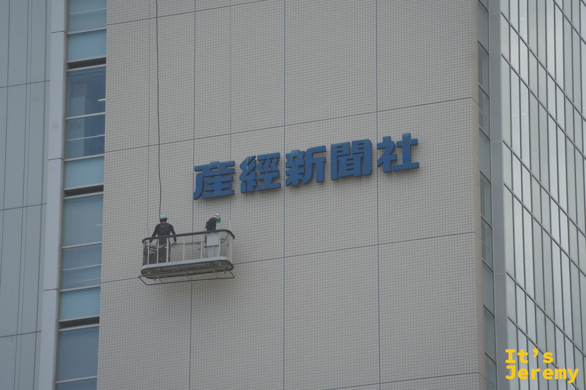 産経新聞社大樓外牆,兩名工人站在吊籠上進行外牆維修作業