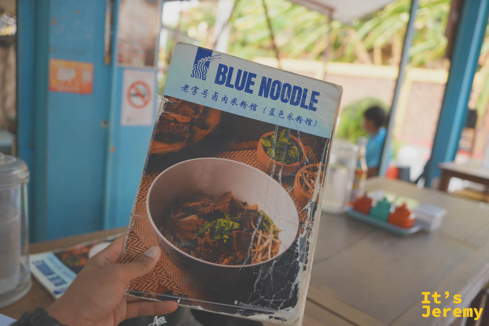 手持 Blue Noodle 菜單，封面寫著「老字號滷肉米粉館（藍色米粉館）」