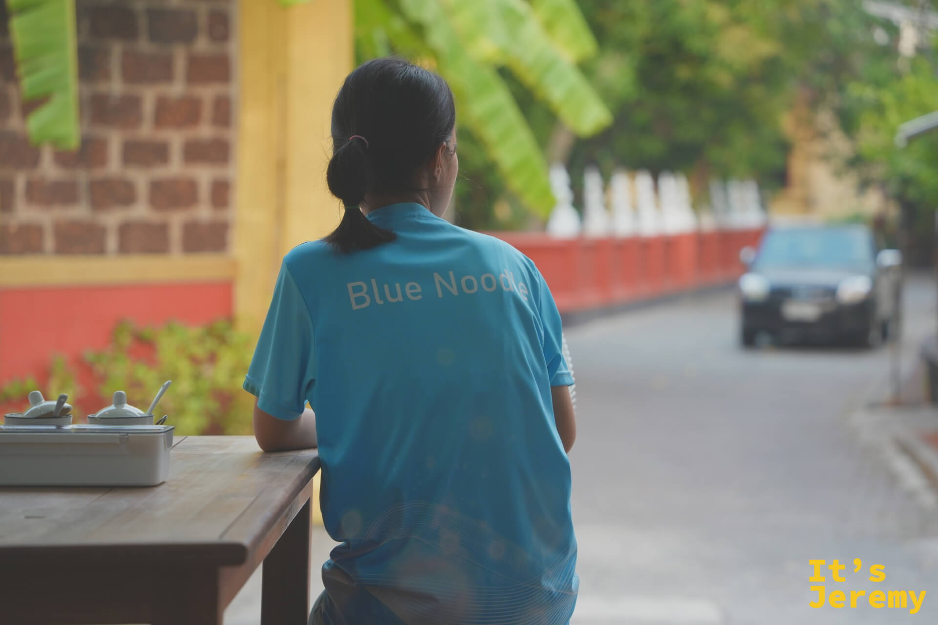 穿 Blue Noodle 制服的女店員背影，望向街道