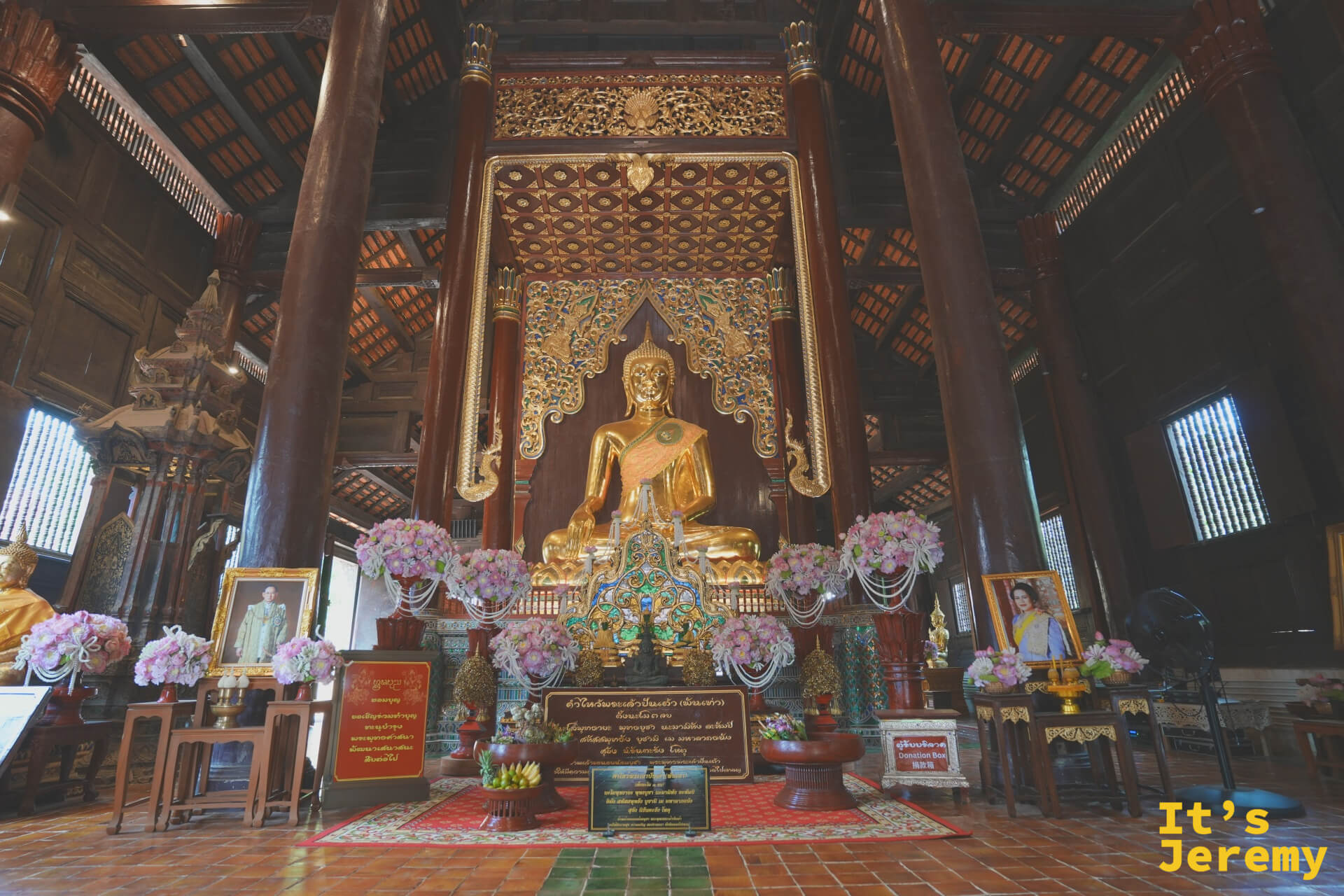 盼道寺大殿全景，金身主佛坐在木造高台上，兩側掛著泰國國王相框
