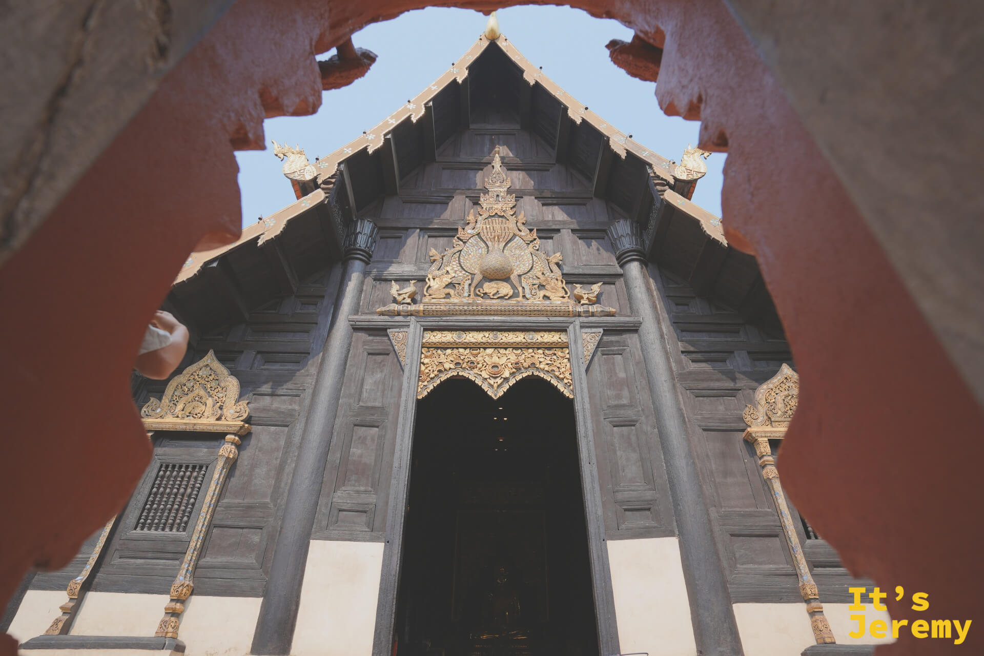 從朱紅院牆缺口望入盼道寺，百年柚木大殿被院牆自然框住