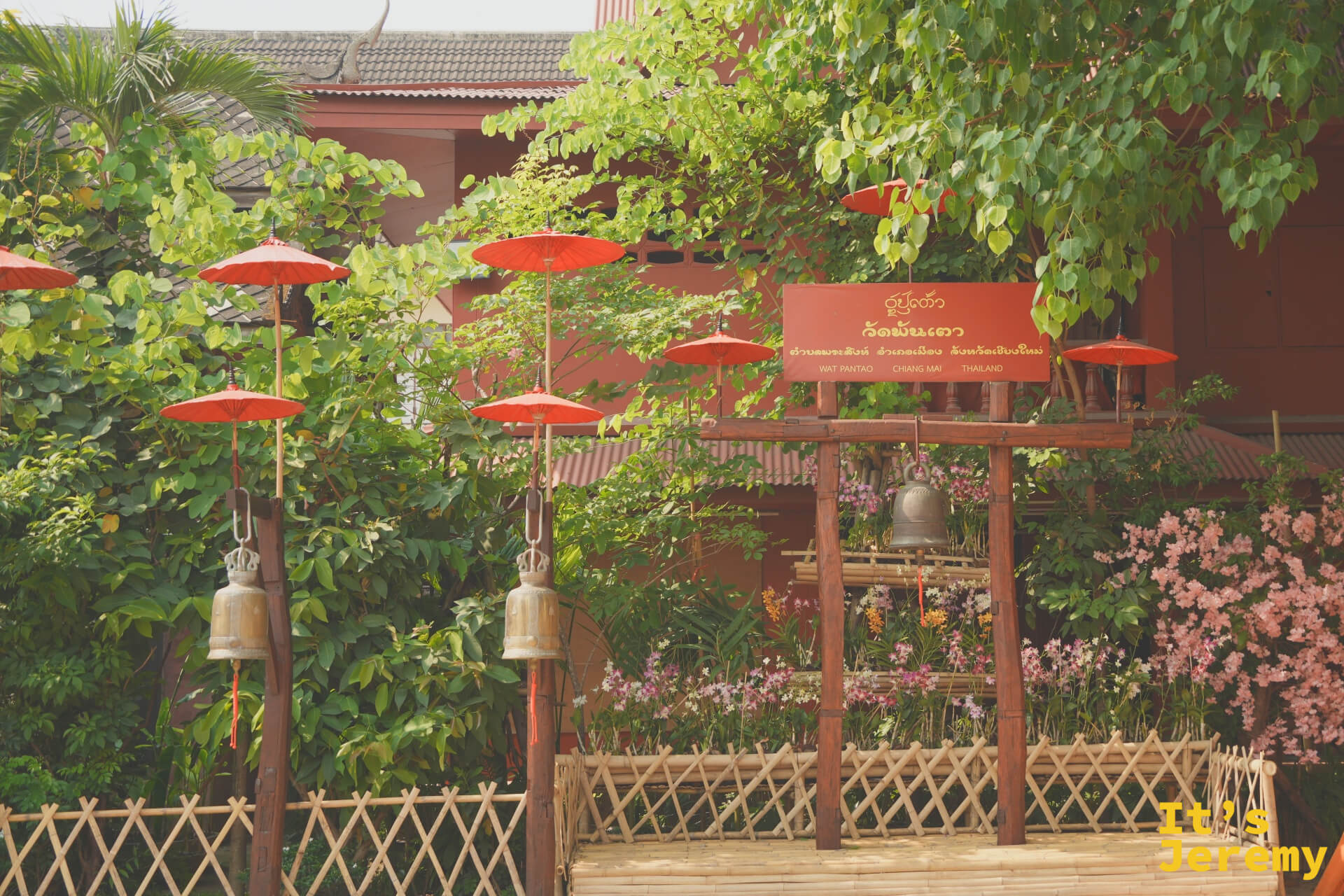 盼道寺入口花園，紅色傘燈、銅鐘排列，竹籬牆上掛著寺廟名牌