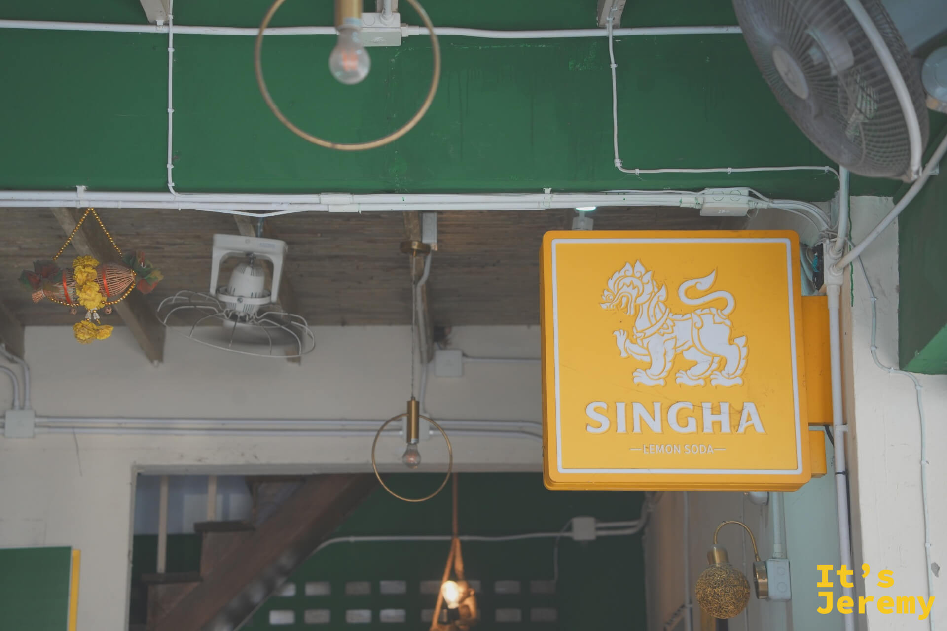 店內 Singha Lemon Soda 黃色燈箱招牌,與綠色天花板對比鮮明