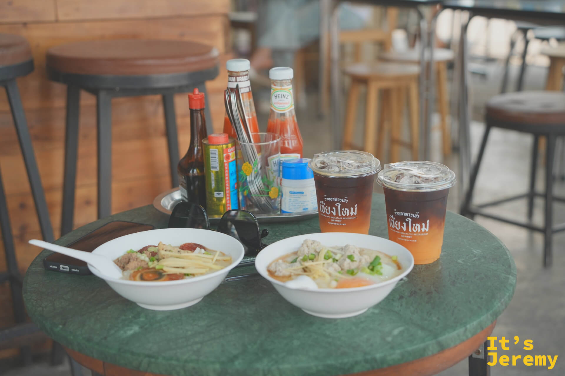 整桌全景:兩碗粥、兩杯 Orange Americano、調味料盤,綠色大理石圓桌