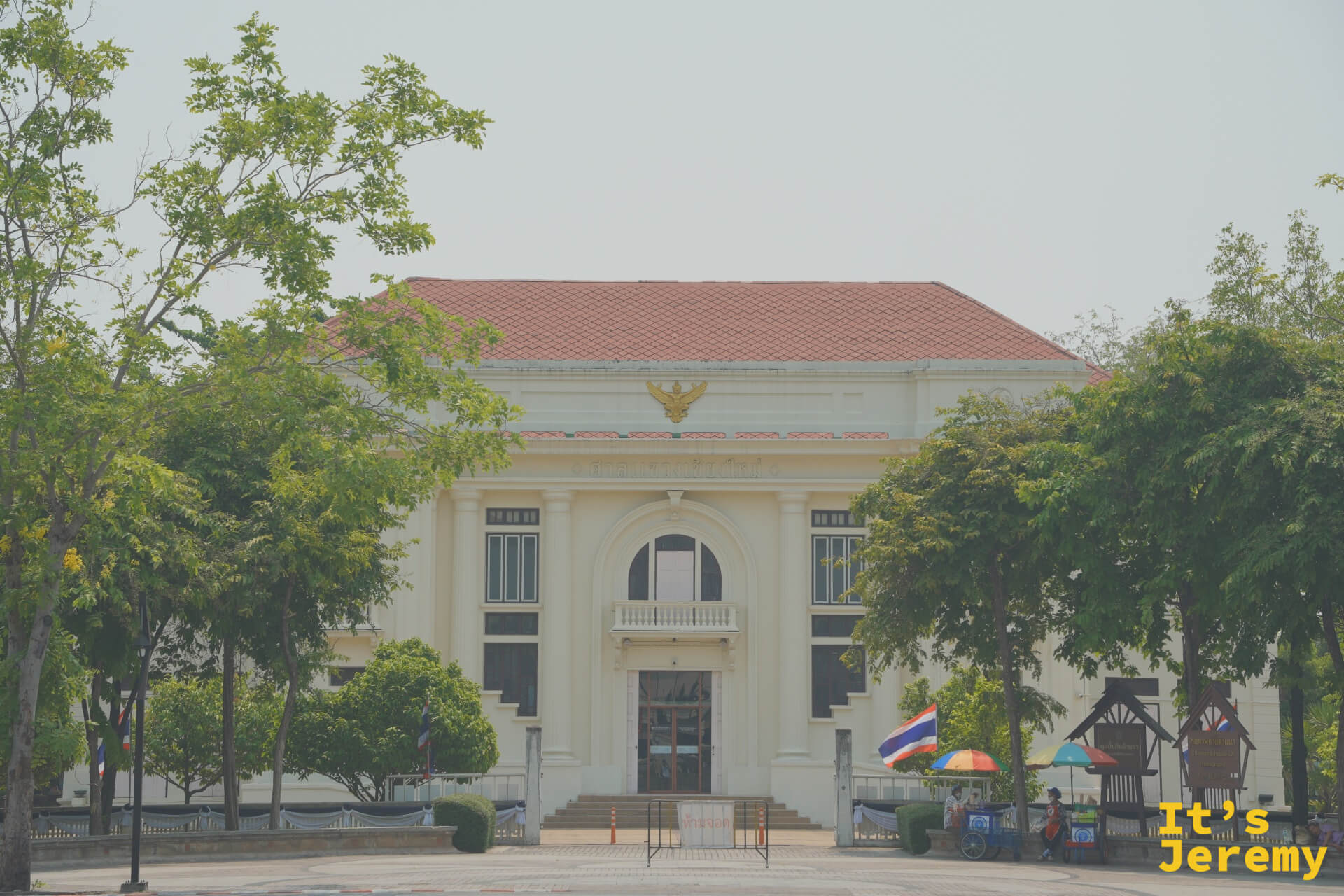 清邁市立藝術文化中心建築全景,透過行道樹望去,歐式立面與橘紅屋瓦在陽光下對比鮮明