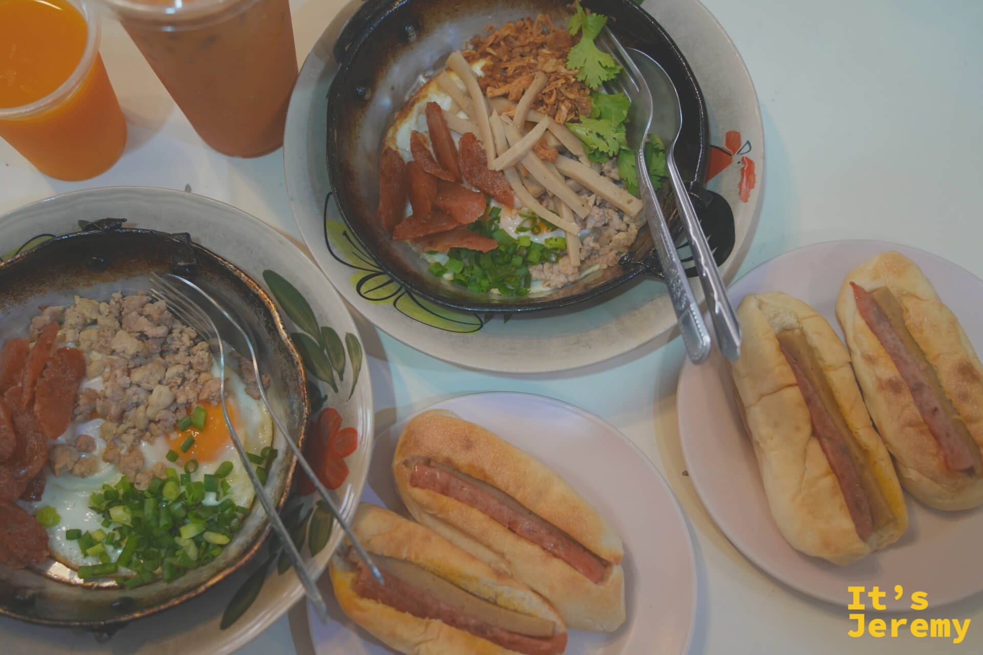 Kai Ka Ta Lert Ros 整桌早餐的俯瞰,鐵鍋、麵包、醬料和配菜一次到齊,橘色桌面上色彩豐富