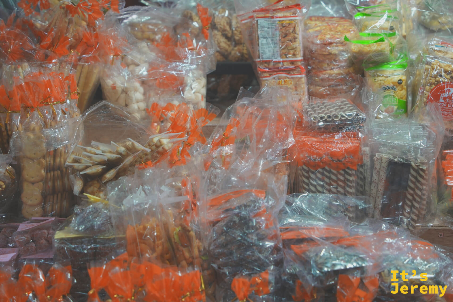 各式餅乾和零食的近景,橘色包裝袋密密麻麻排滿攤位,顏色飽滿層次豐富