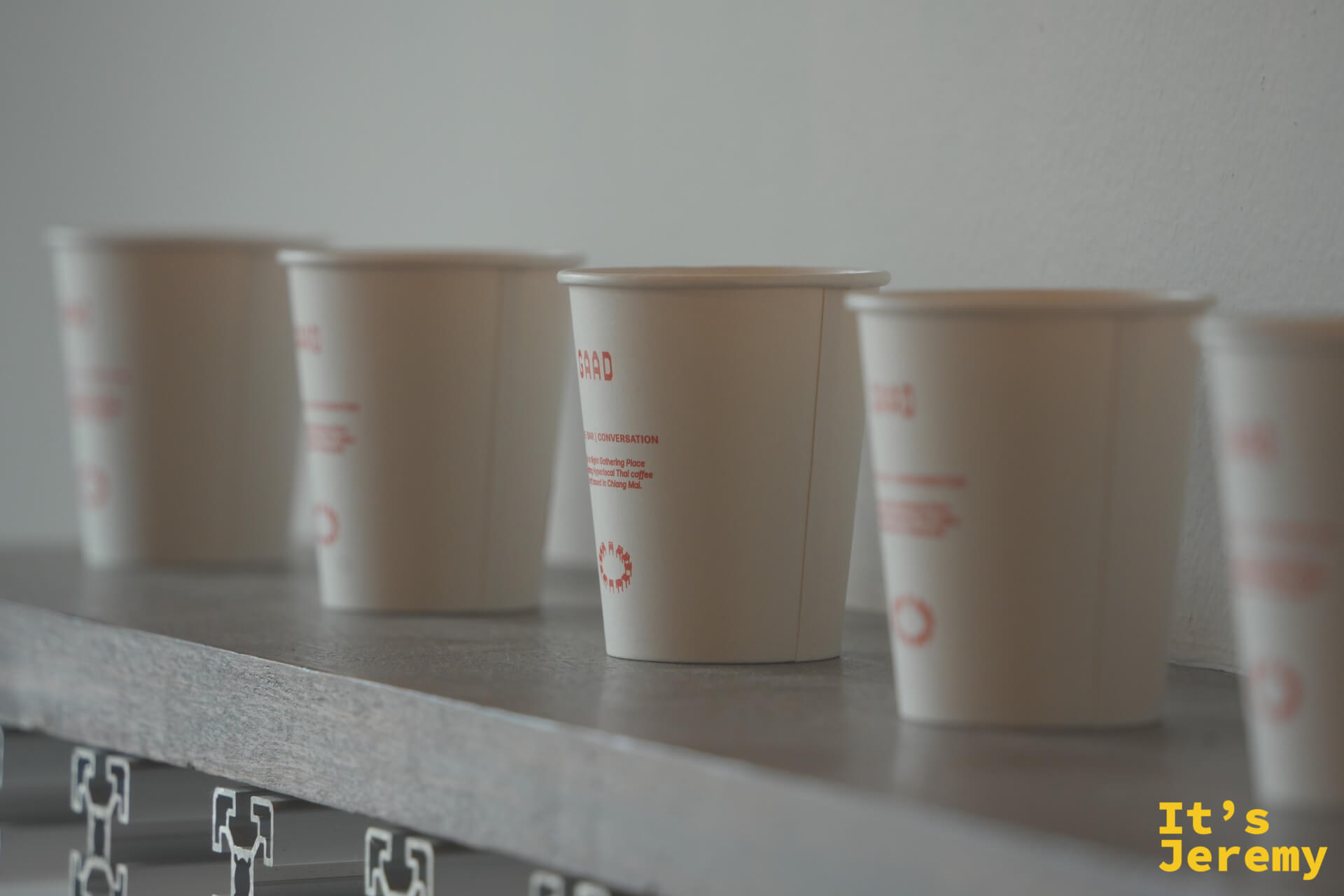 GAAD 紙杯特寫,杯身印著 GAAD、BAR / CONVERSATION 字樣,周圍虛化