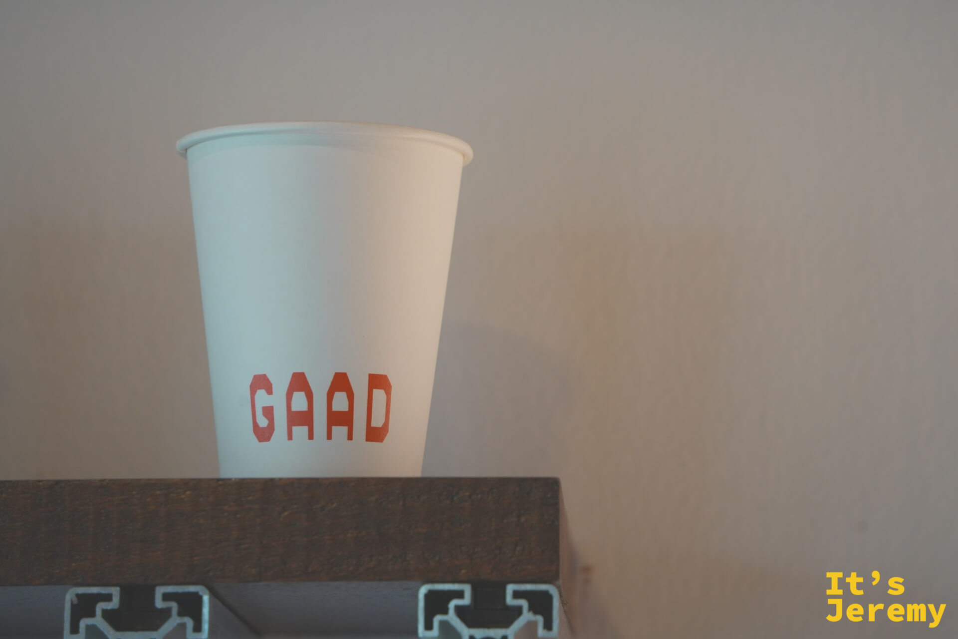單只 GAAD 紙杯在暖光中,紅色 GAAD 字樣清晰