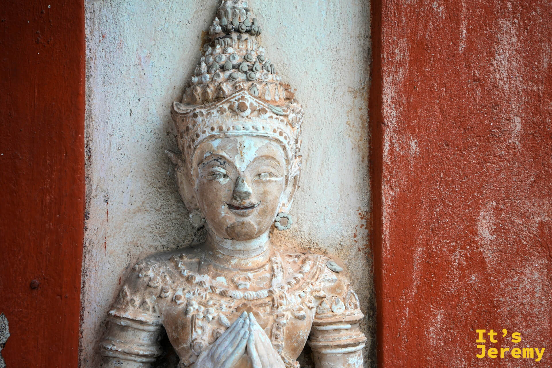 牆壁上的天神合十浮雕,白灰色為底,歲月風化紋理清晰