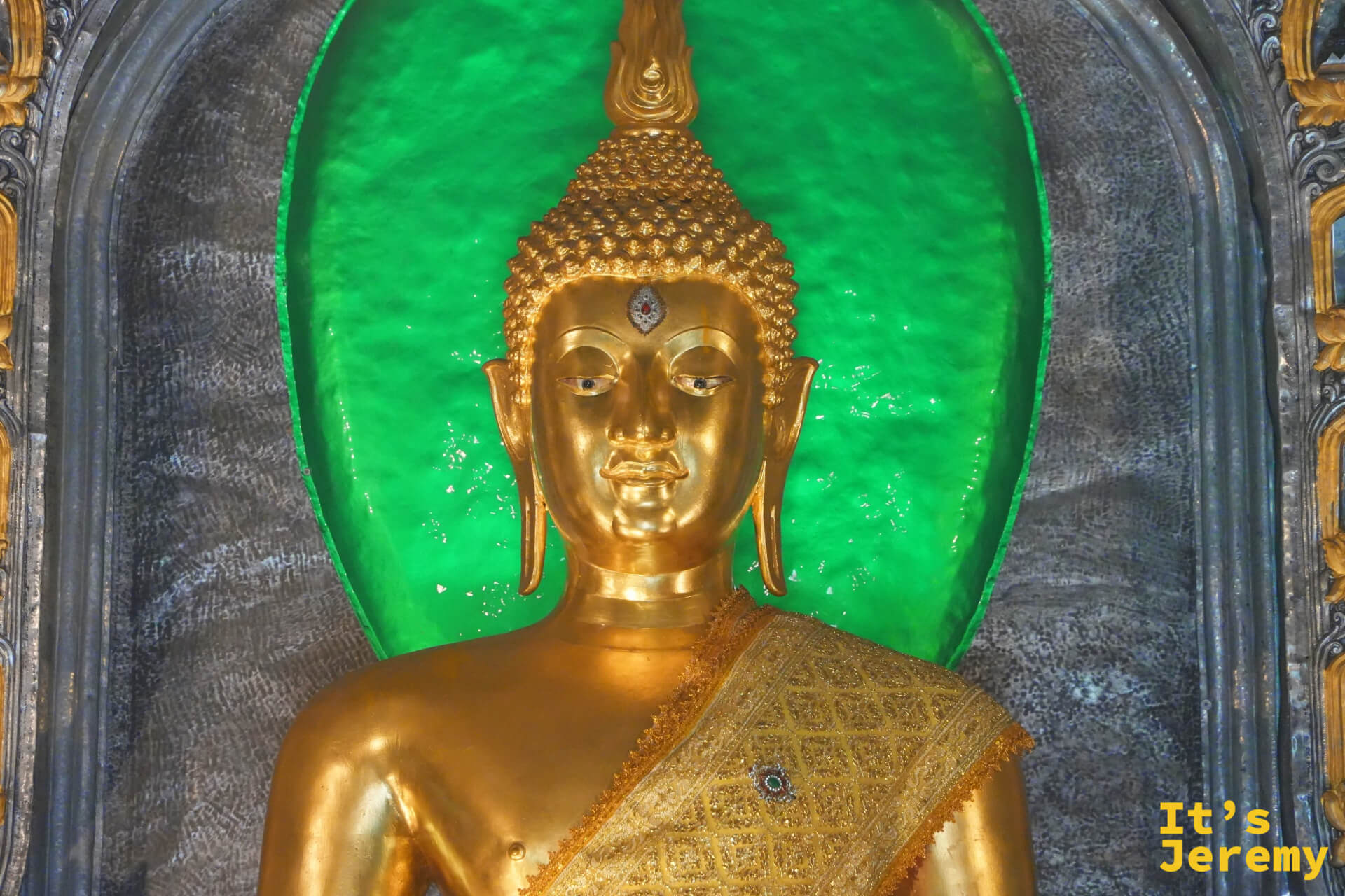 主佛壇中央的金佛特寫，翠綠背光環繞，莊嚴而美麗，是全殿視覺焦點