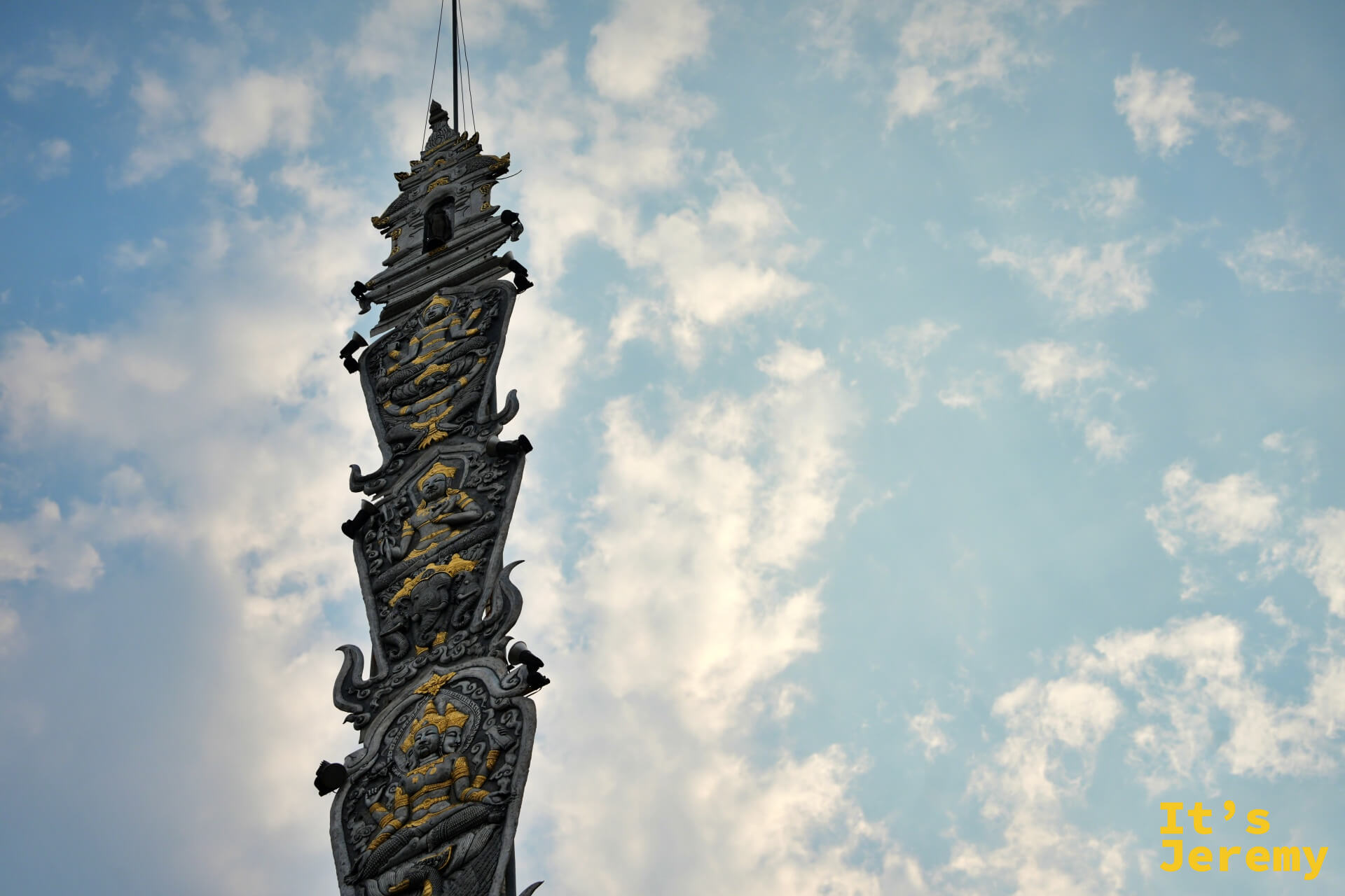 旗幡柱仰拍，金色神明層層排列而上，幾乎消失在天空中