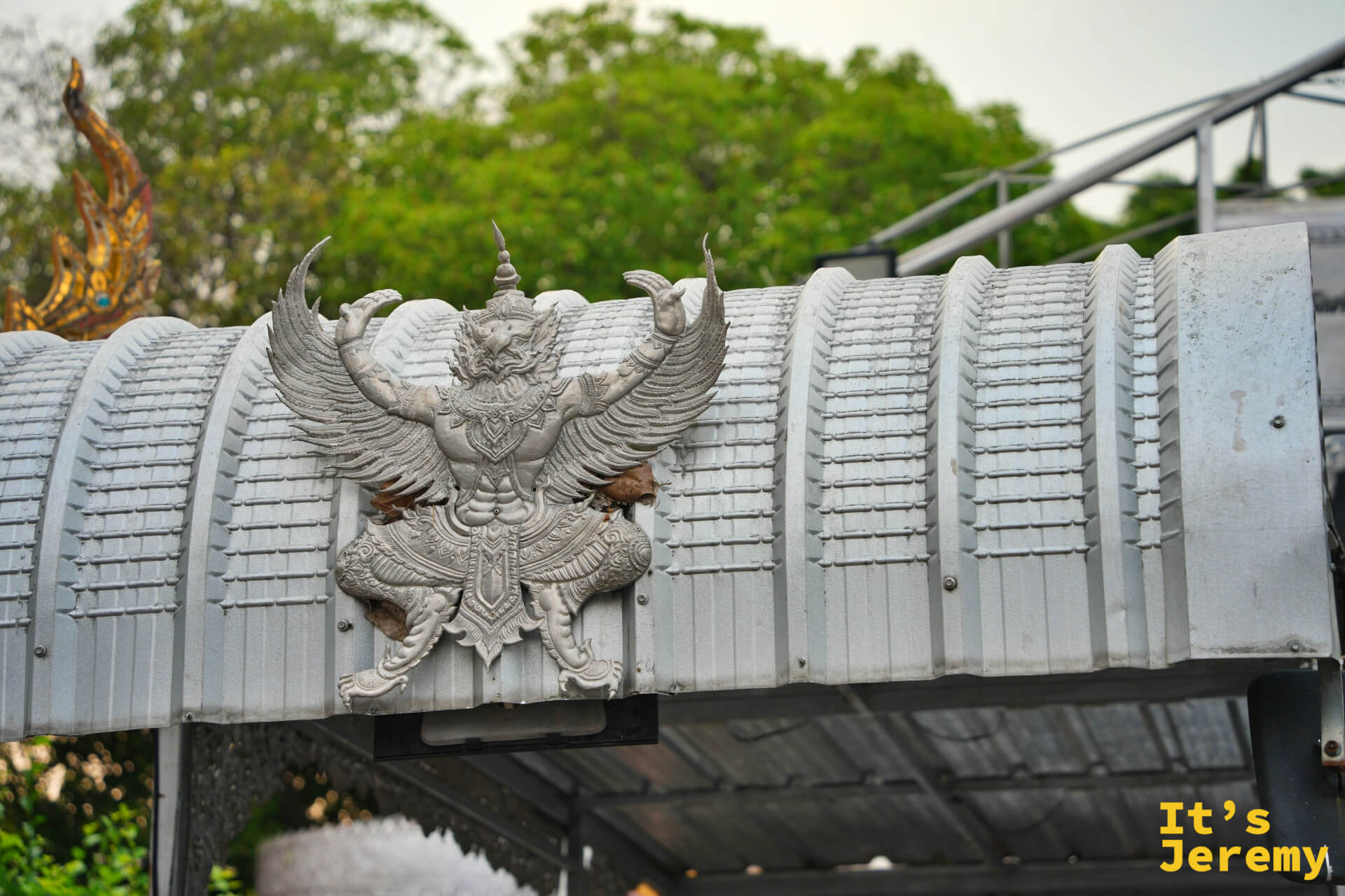 寺廟圍牆上的大鵬金翅鳥（Garuda）浮雕，翅膀全開，銀白色材質更顯威嚴
