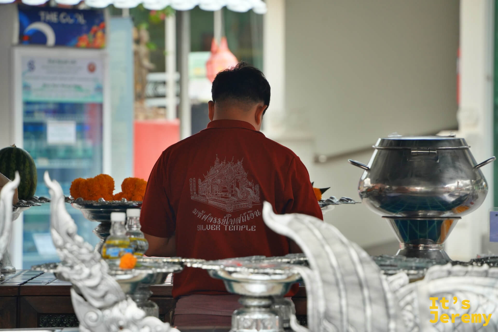 穿著印有銀殿圖案紅色制服的工作人員，正在整理供台，供品整齊擺放