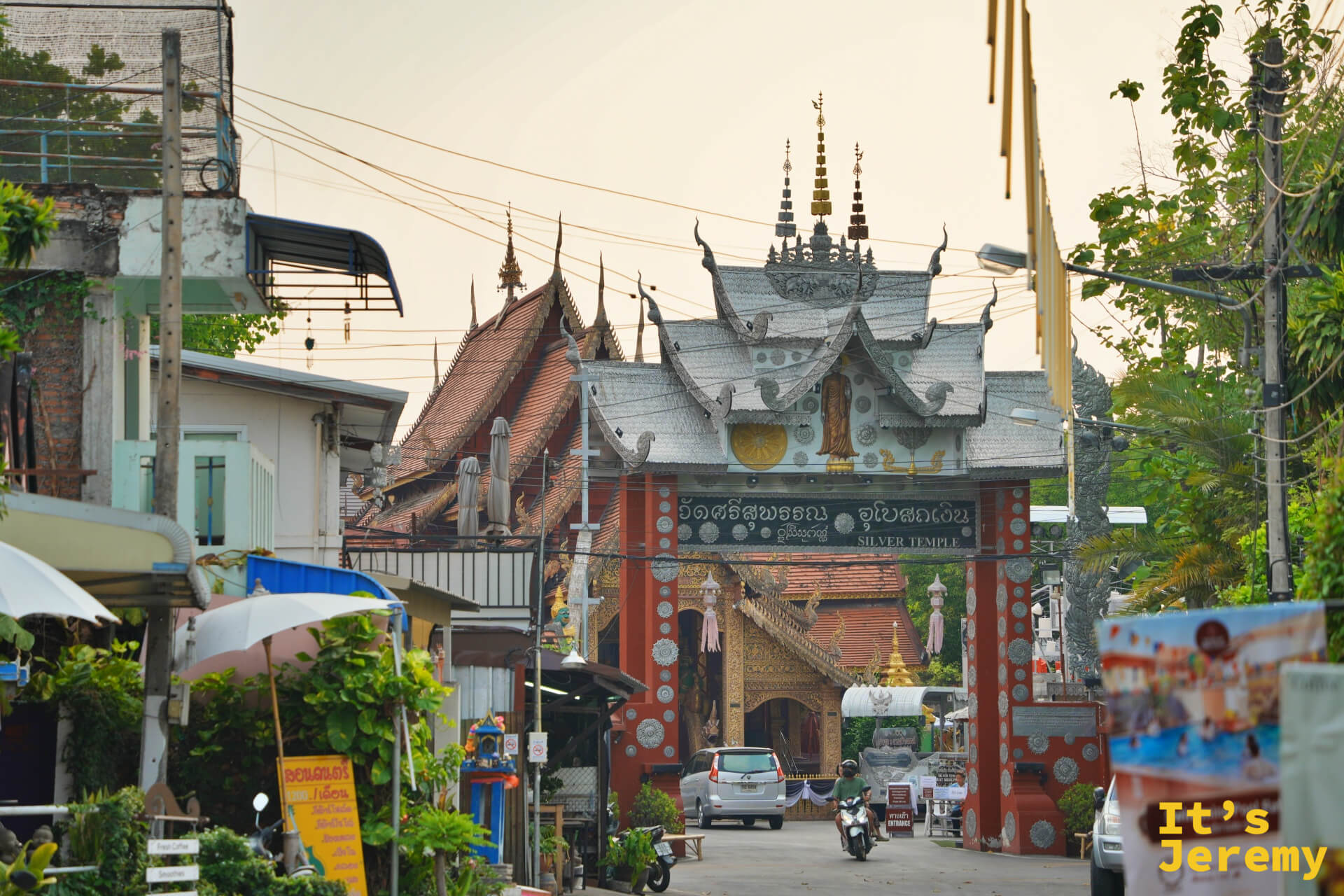 傍晚從 วัวลาย 路望向銀殿大門，入口招牌就嵌在街道正中央