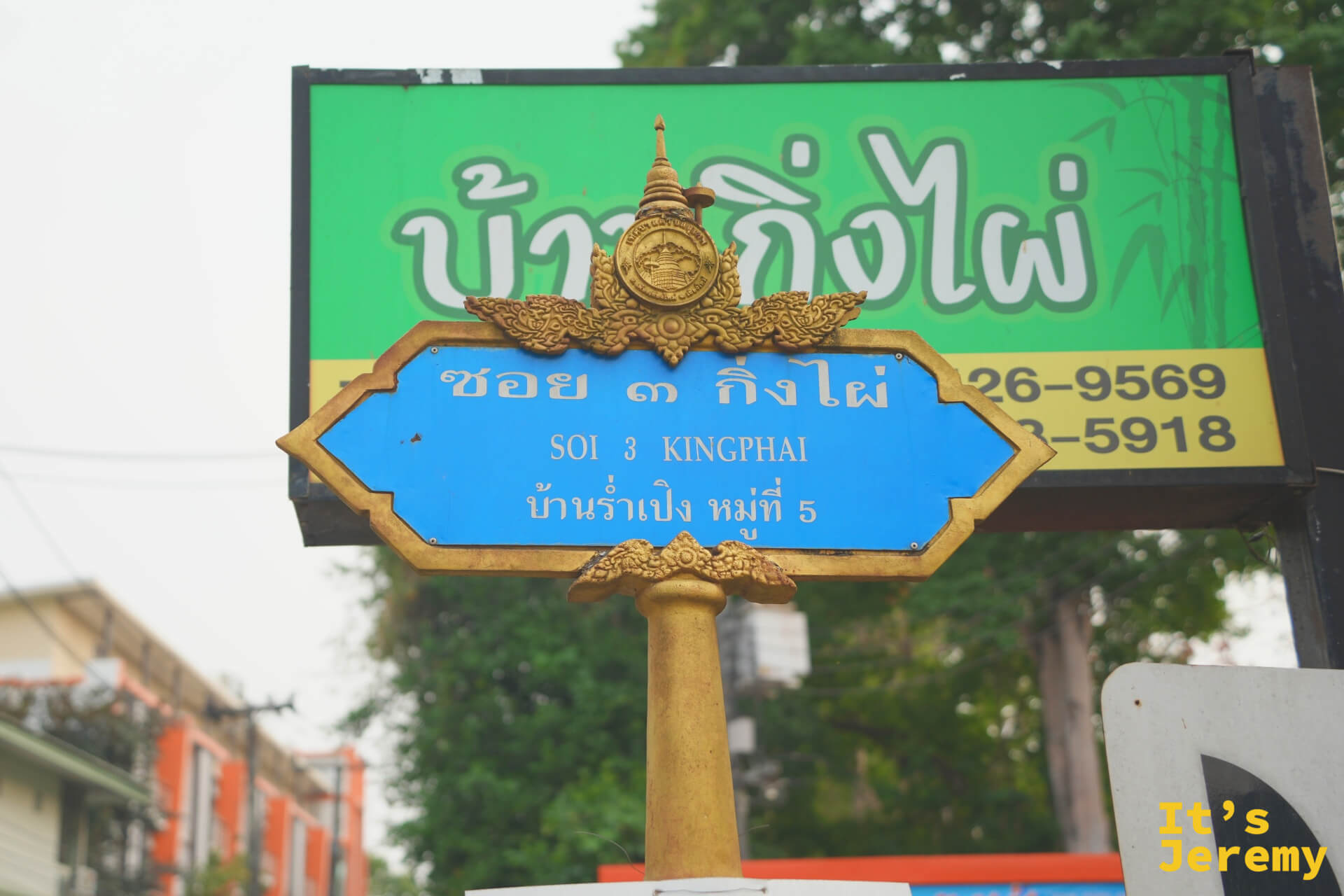 蘭納式金色雕飾的藍底路牌,寫著 Soi 3 Kingphai,後方是綠底泰文招牌