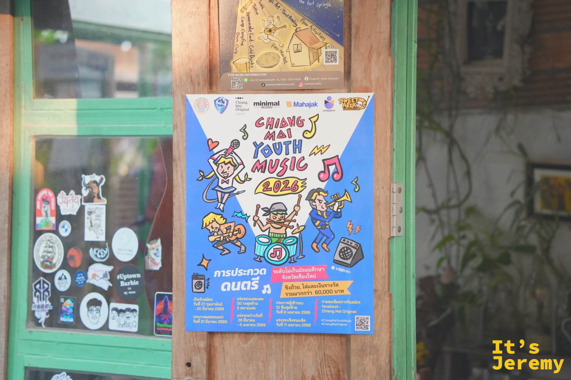 木門柱上貼著「Chiang Mai Youth Music 2026」的彩色海報,門玻璃上滿是各式貼紙,充滿文青感