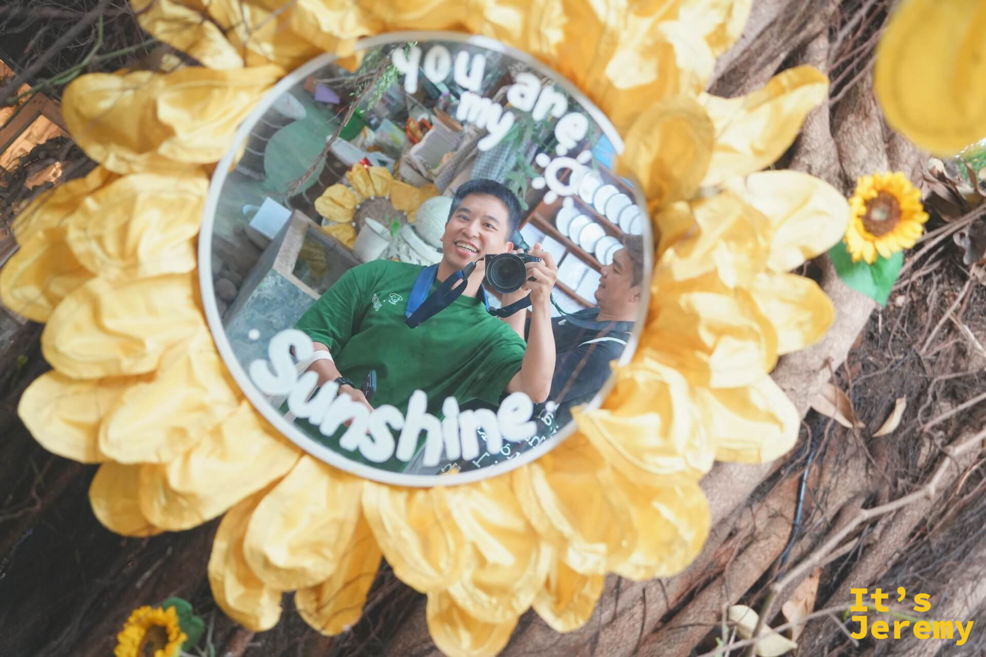 向日葵花框圓鏡俯拍,鏡面寫著「you are my sunshine」,鏡中倒映著拿相機的笑著的訪客