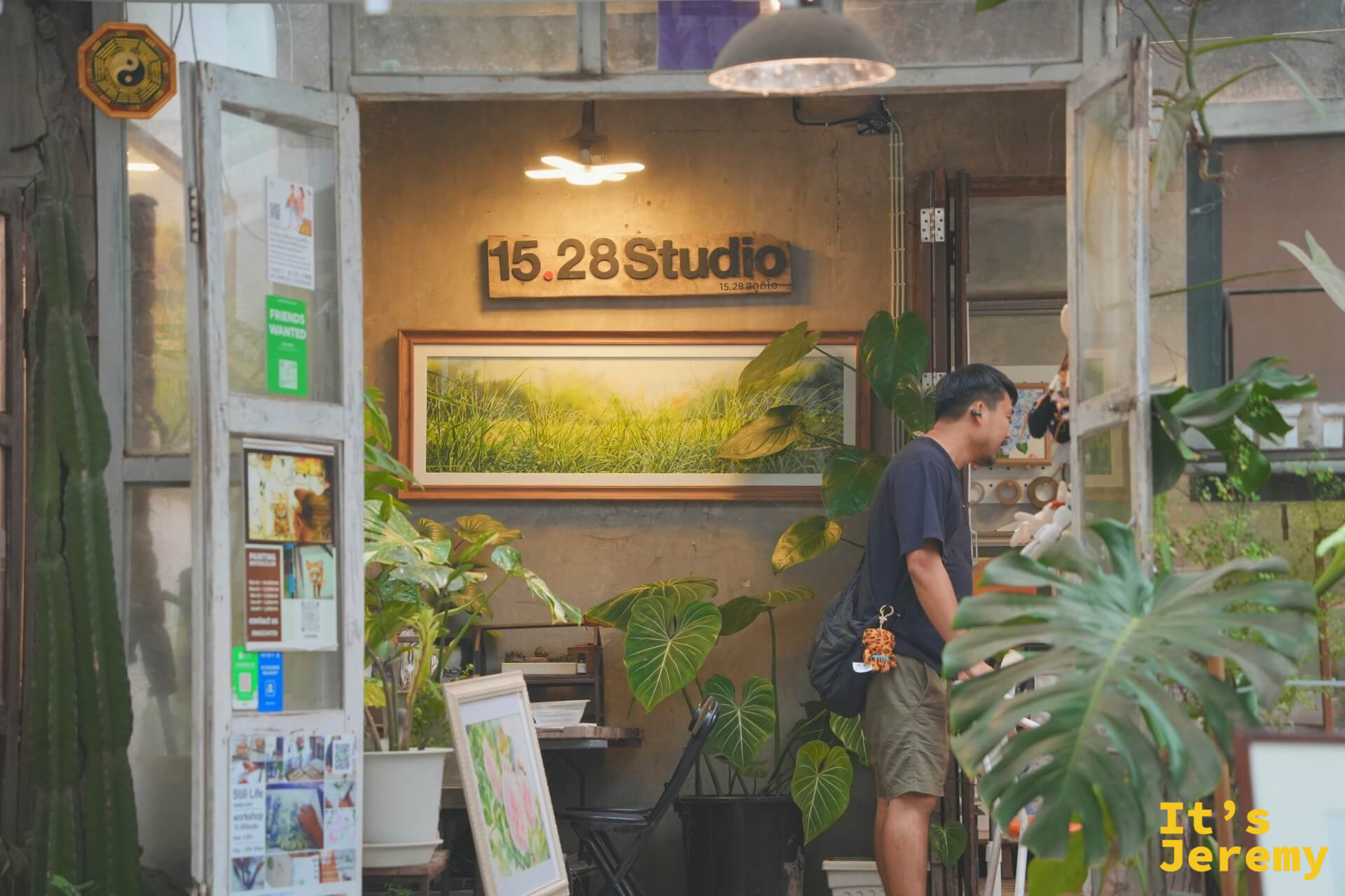 15.28 Studio 店鋪玻璃門內,牆上掛著大幅稻田風景畫,燈光溫暖,一位男生在門口瀏覽