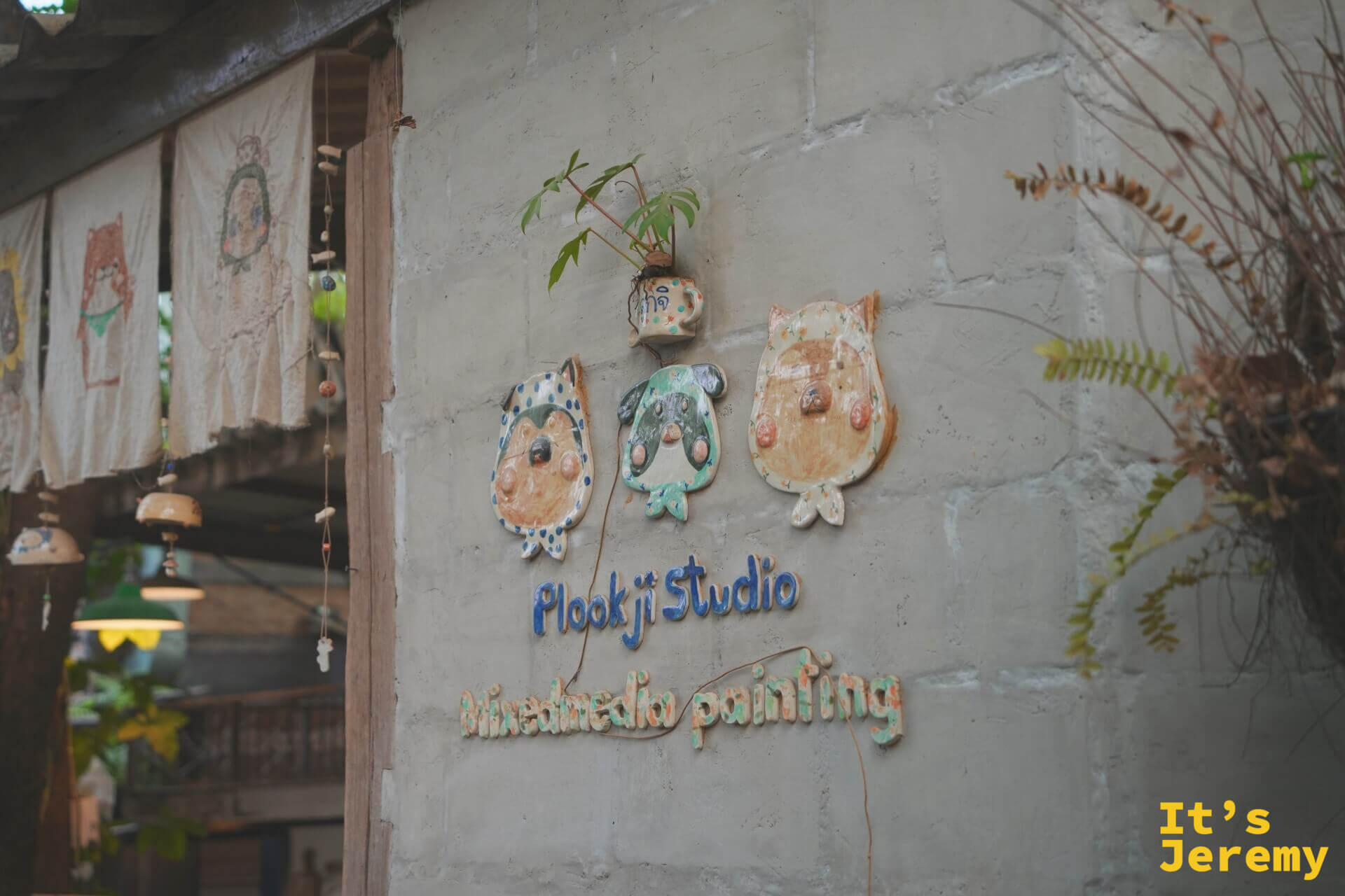 Plookji Studio 工作室外牆,有三隻手捏陶瓷貓頭鷹裝飾,下方是藍色陶瓷字「Plookji Studio Mixed media painting」