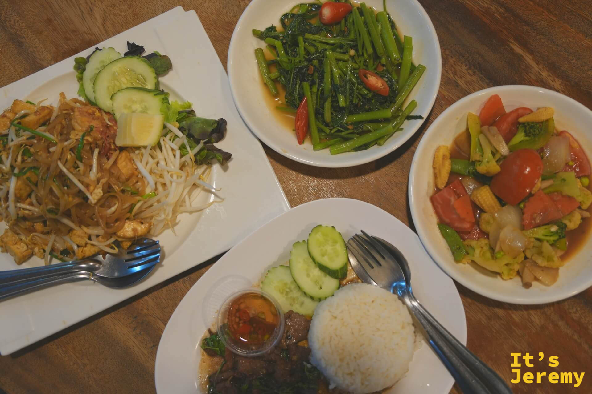 四道菜同框俯拍:泰式炒河粉、炒空心菜、炒綜合蔬菜、牛肉打拋飯,木質桌面背景