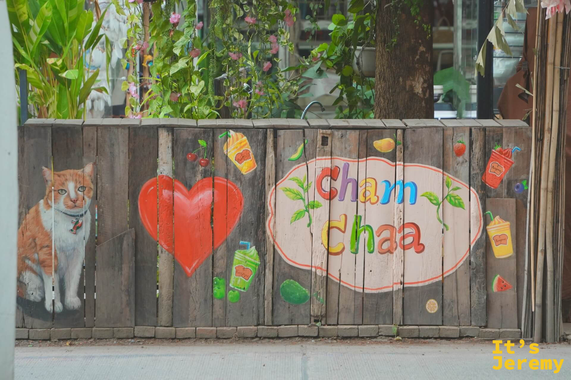 木板牆上的 Cham Chaa 彩繪招牌,旁邊畫著一隻橘貓和大紅愛心
