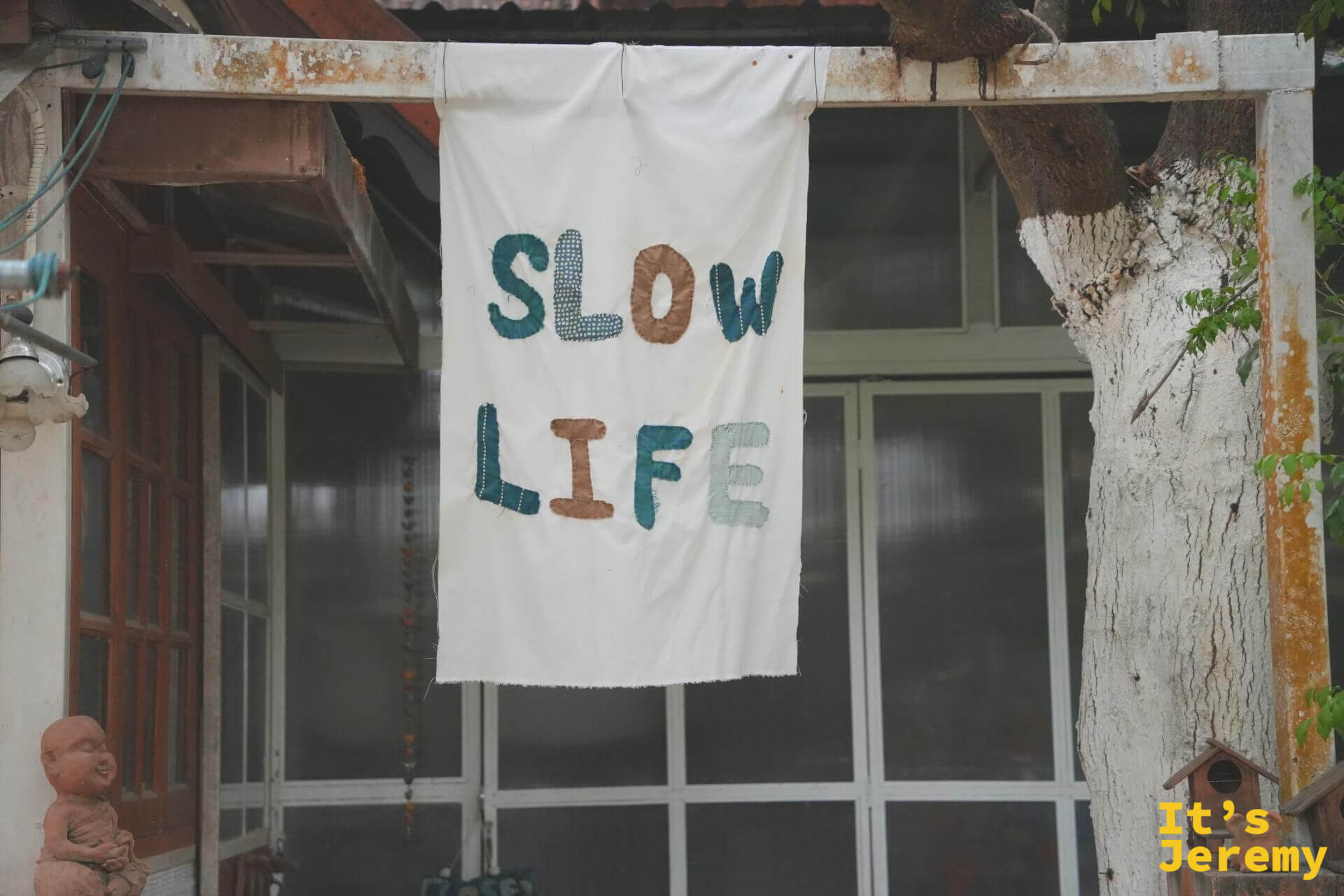 老屋簷下掛著布拼貼的「SLOW LIFE」白布旗