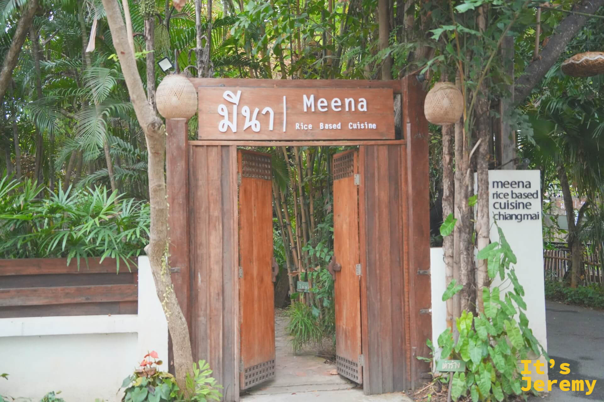 Meena 的木牌坊入口，木雕大門敞開，招牌寫著 มีนา Meena Rice Based Cuisine