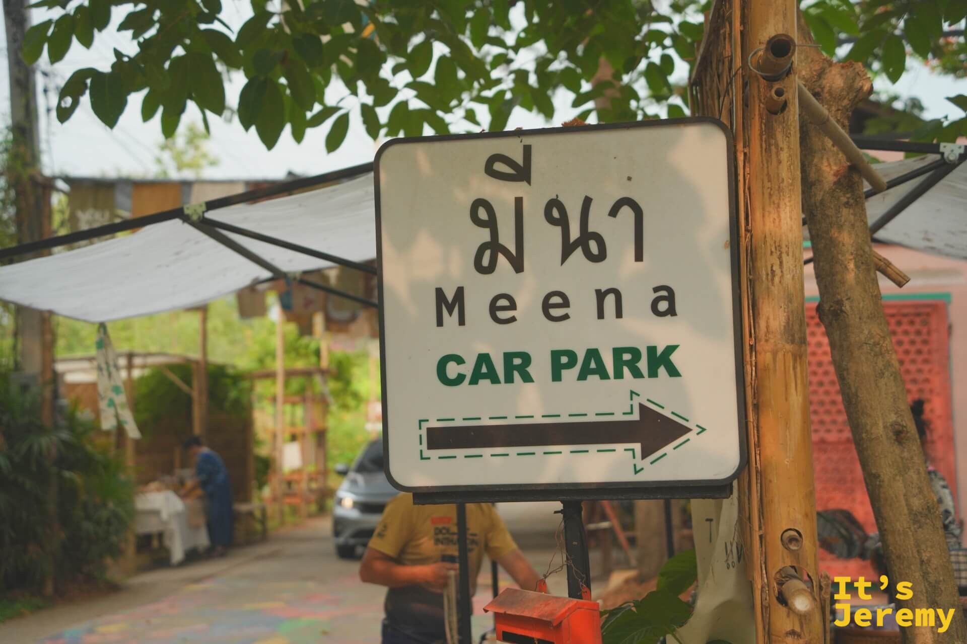 Meena CAR PARK 白色指標牌，咖啡色箭頭指向停車場方向