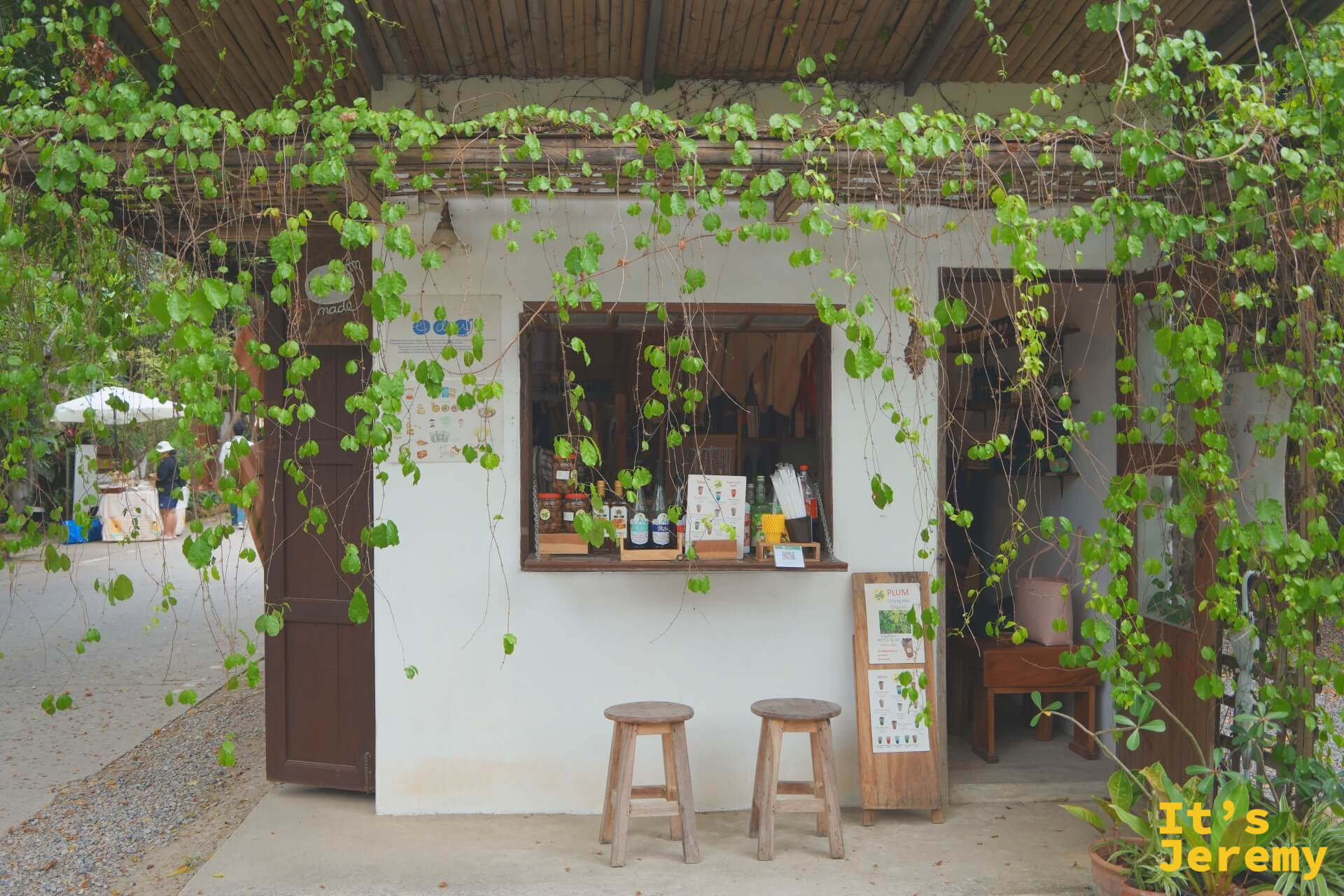 EDUMade 的白色小屋店面,藤蔓從棚架垂落成綠簾,點餐口前擺著兩張木凳