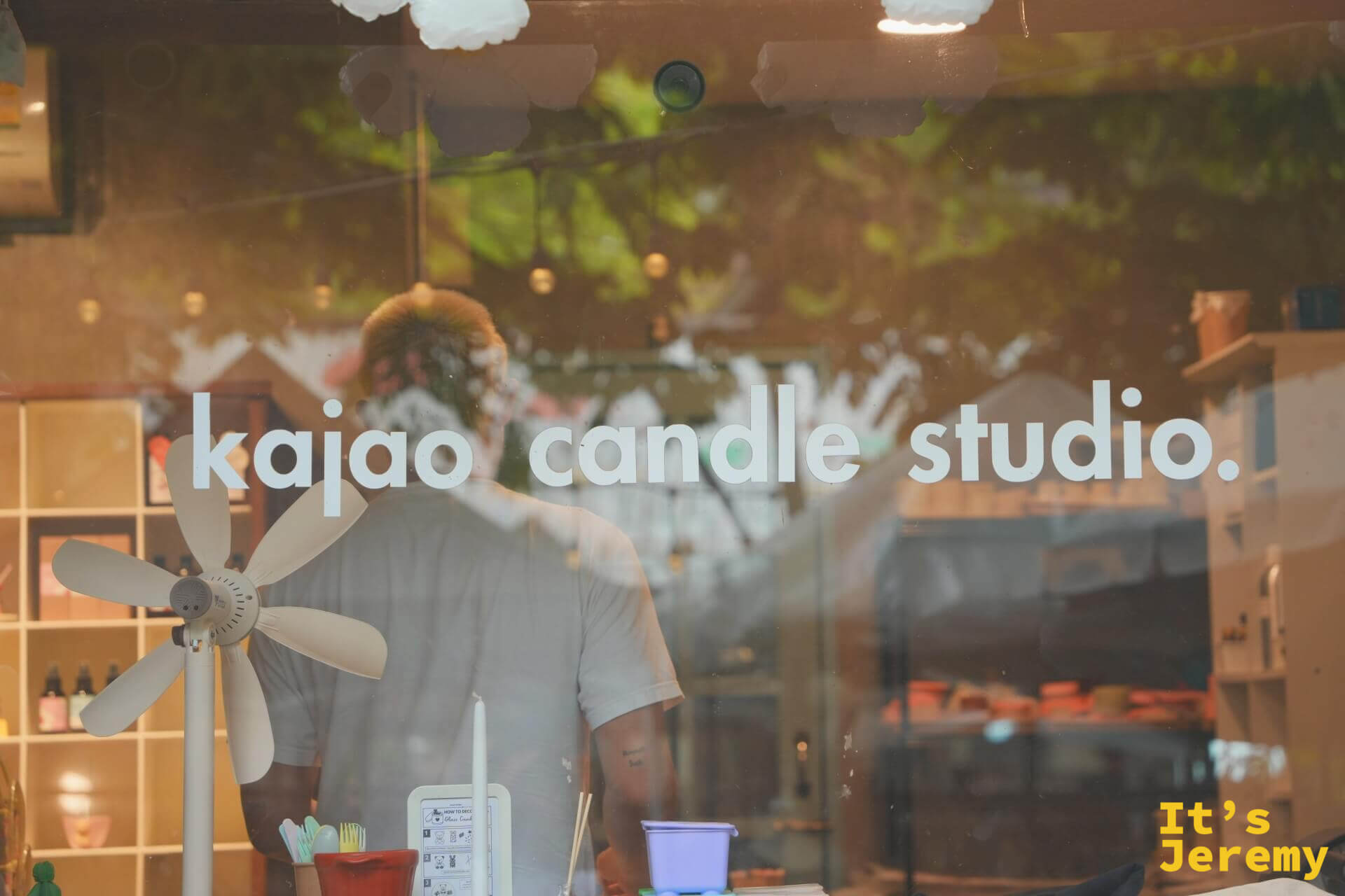 透過玻璃看 kajao candle studio 內部,玻璃上印著店名,映著外面的樹影