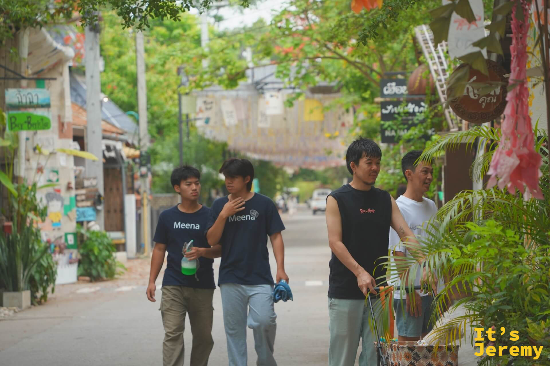 穿著 Meena 字樣 T 恤的店員們走在市集主街上,頭頂是布條天棚