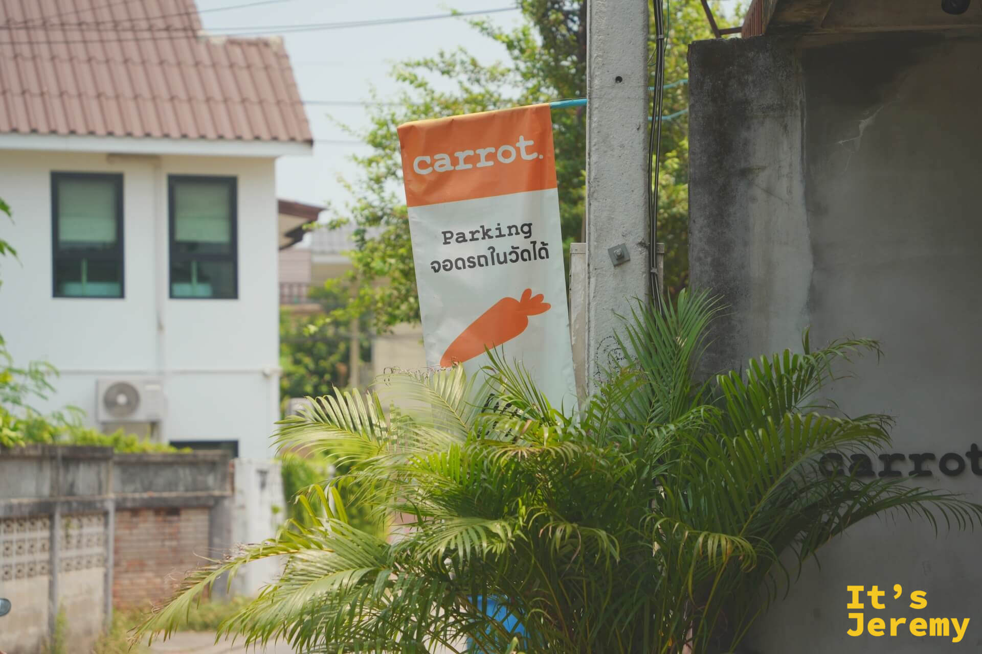 巷口的橘色 carrot 停車旗，寫著可將車停在寺廟內