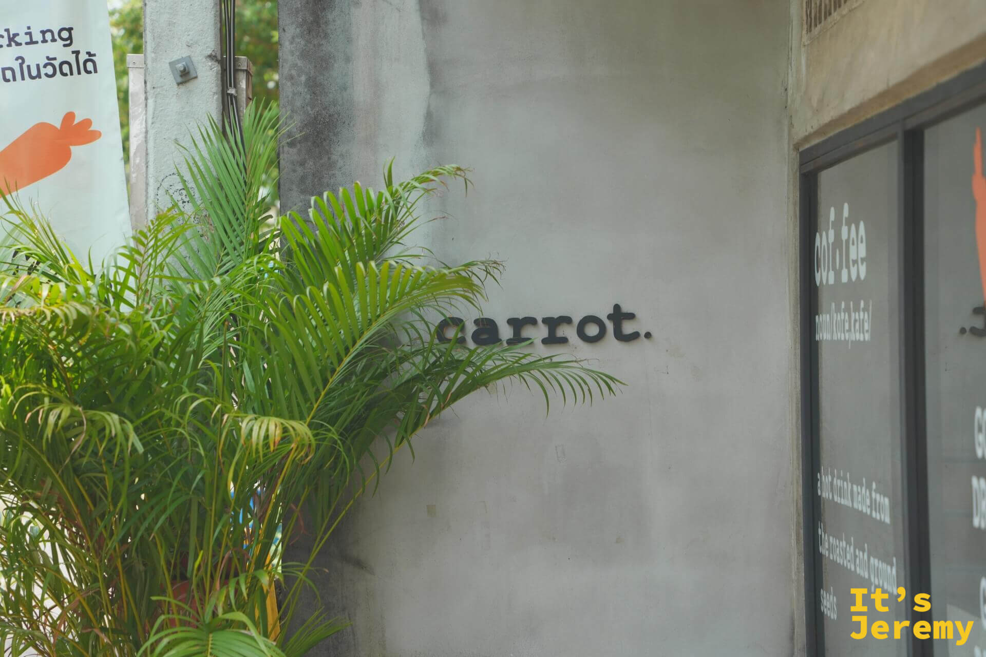 外牆上的 carrot. 字樣與棕櫚盆栽，旁邊就是停車指引旗