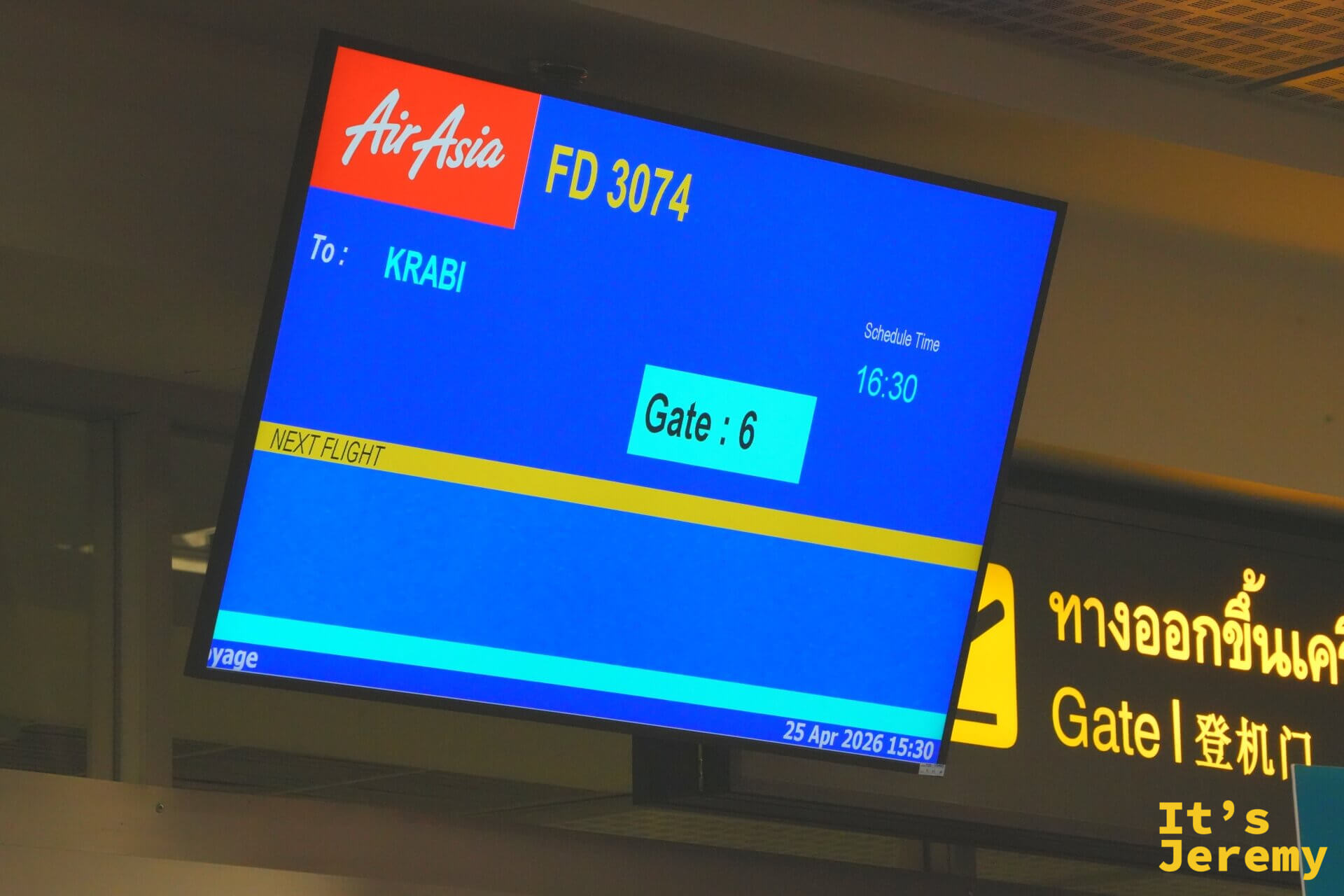 登機門上方的螢幕顯示 AirAsia 飛往喀比的班機資訊,旁邊是黃色的登機門指標
