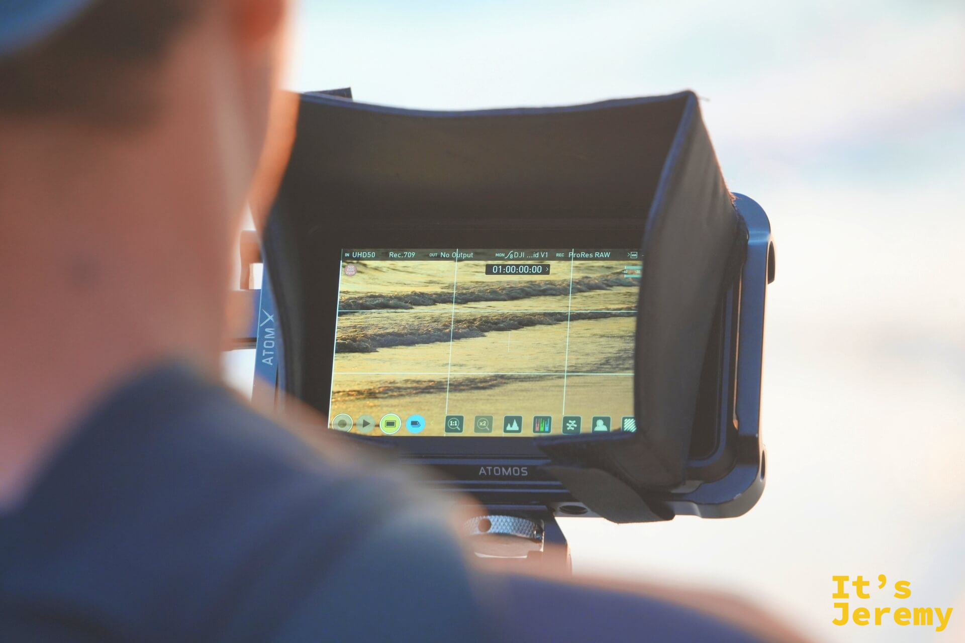 一名創作者手持 Atomos 外接螢幕，螢幕上顯示正在拍攝的海浪畫面