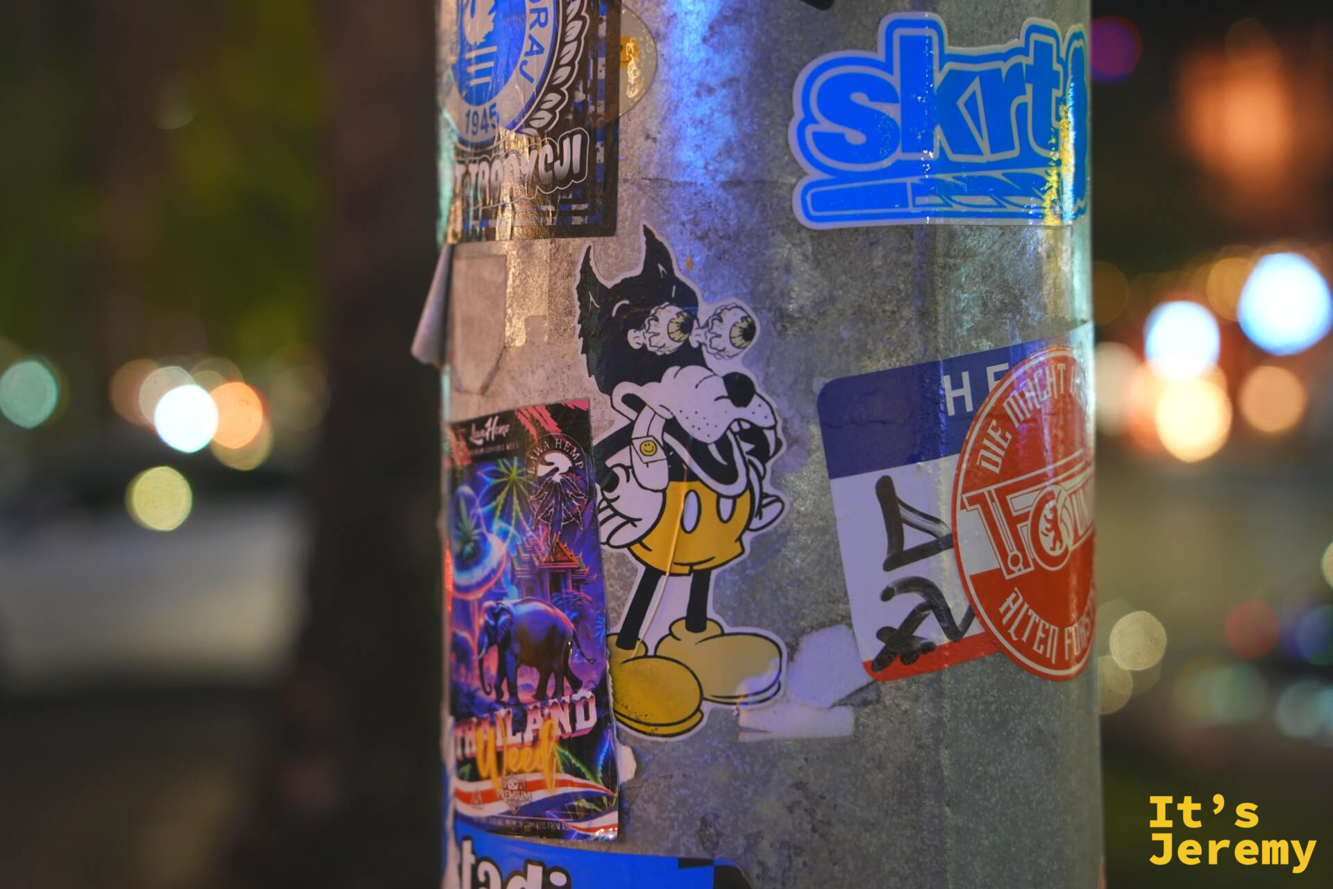電線桿上的創作系貼紙，包括一隻惡魔化的卡通角色與泰國旅遊貼紙