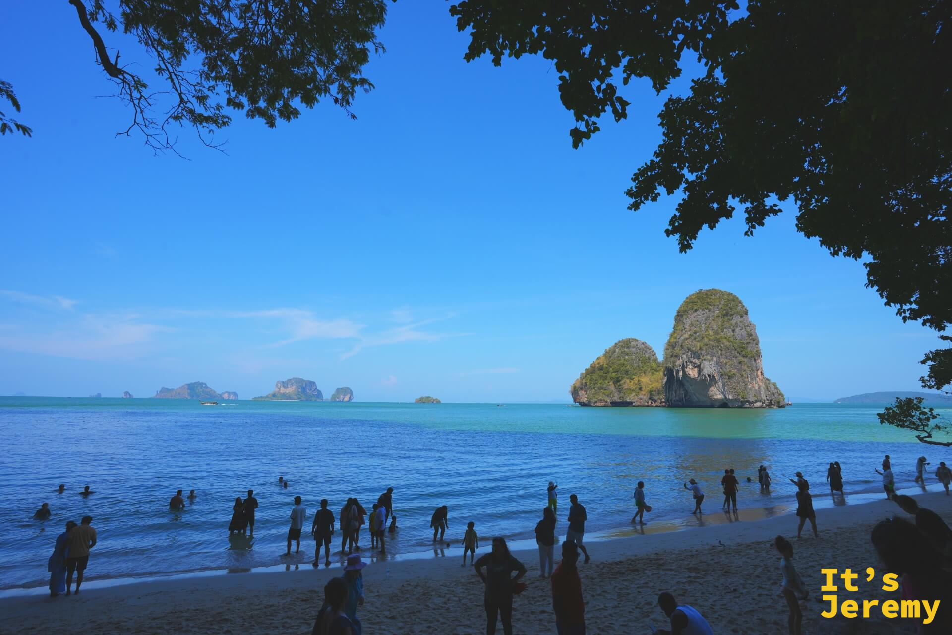 帕南海灘的翡翠綠海水和石灰岩島嶼，沙灘上擠滿各國旅客