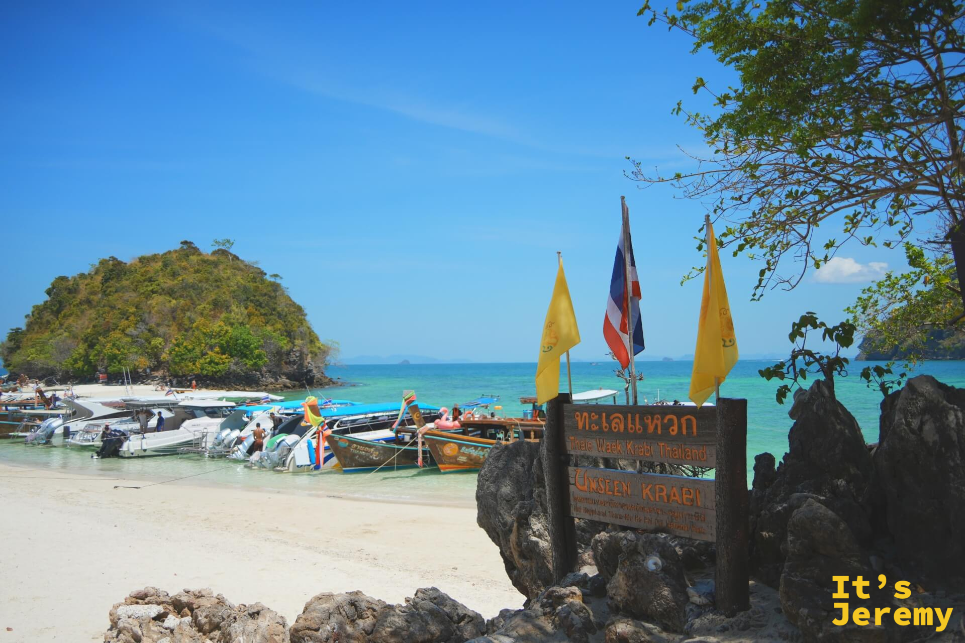 ทะเลแหวก Thale Waek 木製標示牌,「Unseen Krabi」字樣,背後是停靠的長尾船與小島