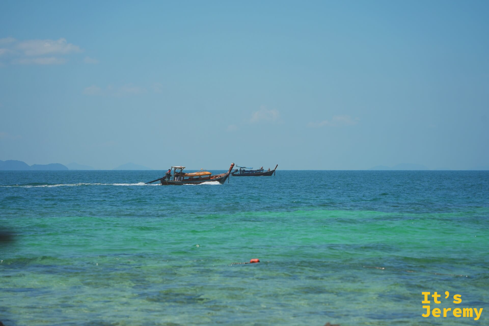 兩艘長尾船行駛在翡翠綠的開闊海面上,水色清澈見底
