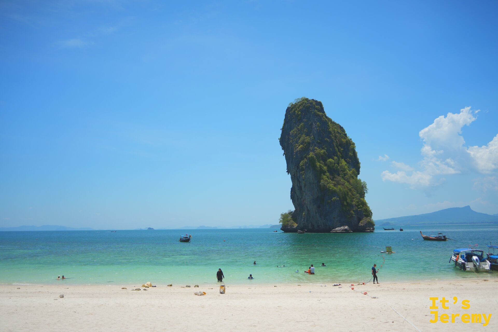 沙灘全景，孤岩與多艘長尾船停靠在岸邊