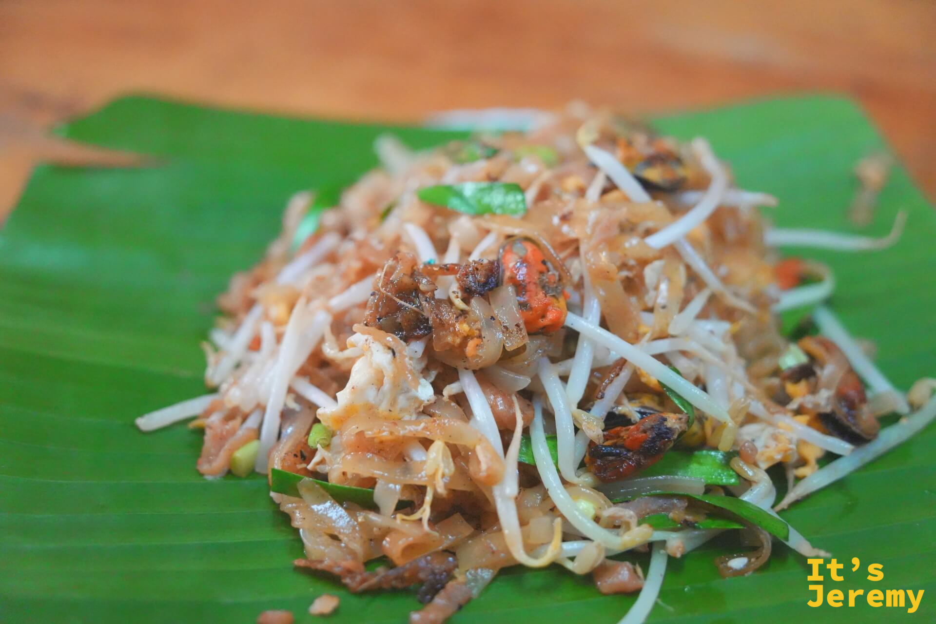 Pad Thai 特寫：米粉帶著微焦色澤，豆芽白嫩，頂上點綴著炒蒜與蝦