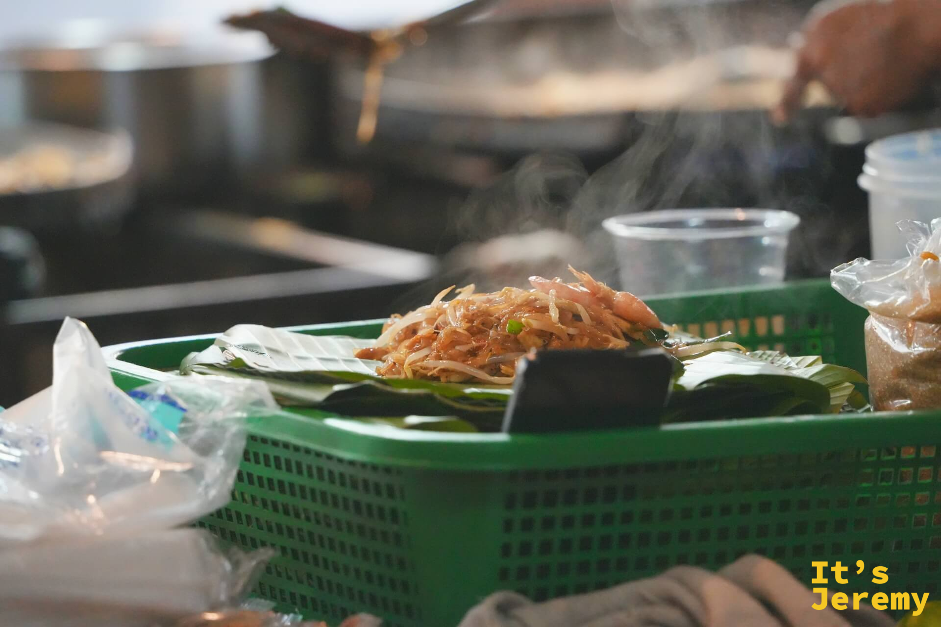 剛炒好的 Pad Thai 盛在芭蕉葉上，豆芽、韭菜和蝦子鋪在米粉頂端，還在冒煙