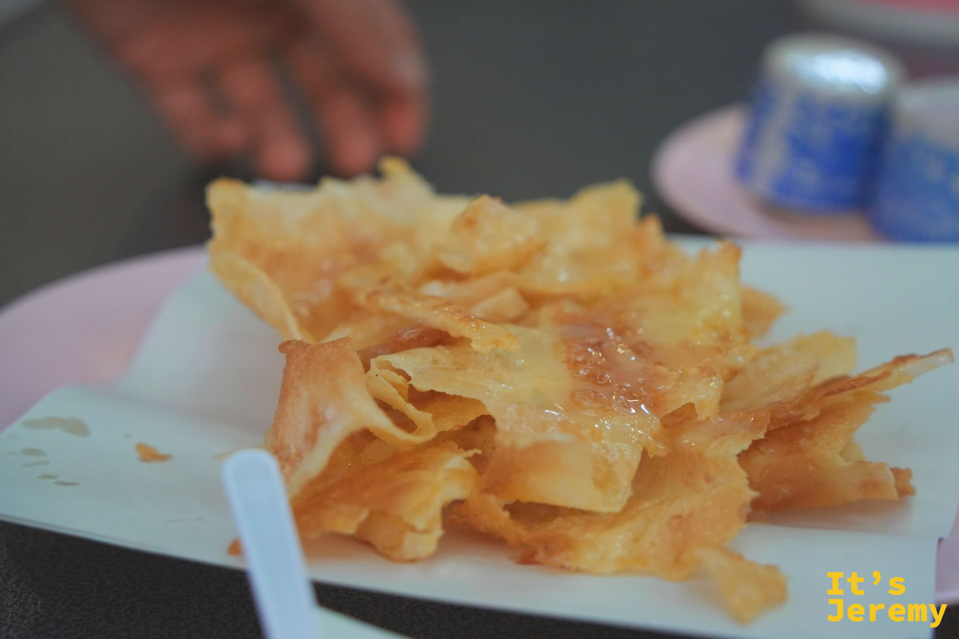 薄脆金黃的 Roti 餅皮堆疊在白色盤上，碎裂邊緣沾著焦糖光澤。