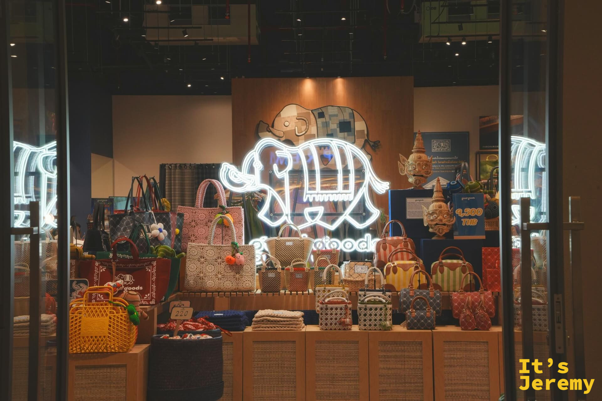 goodgoods 品牌店面櫥窗,展示多款泰式編織包包,背後有大象造型霓虹燈