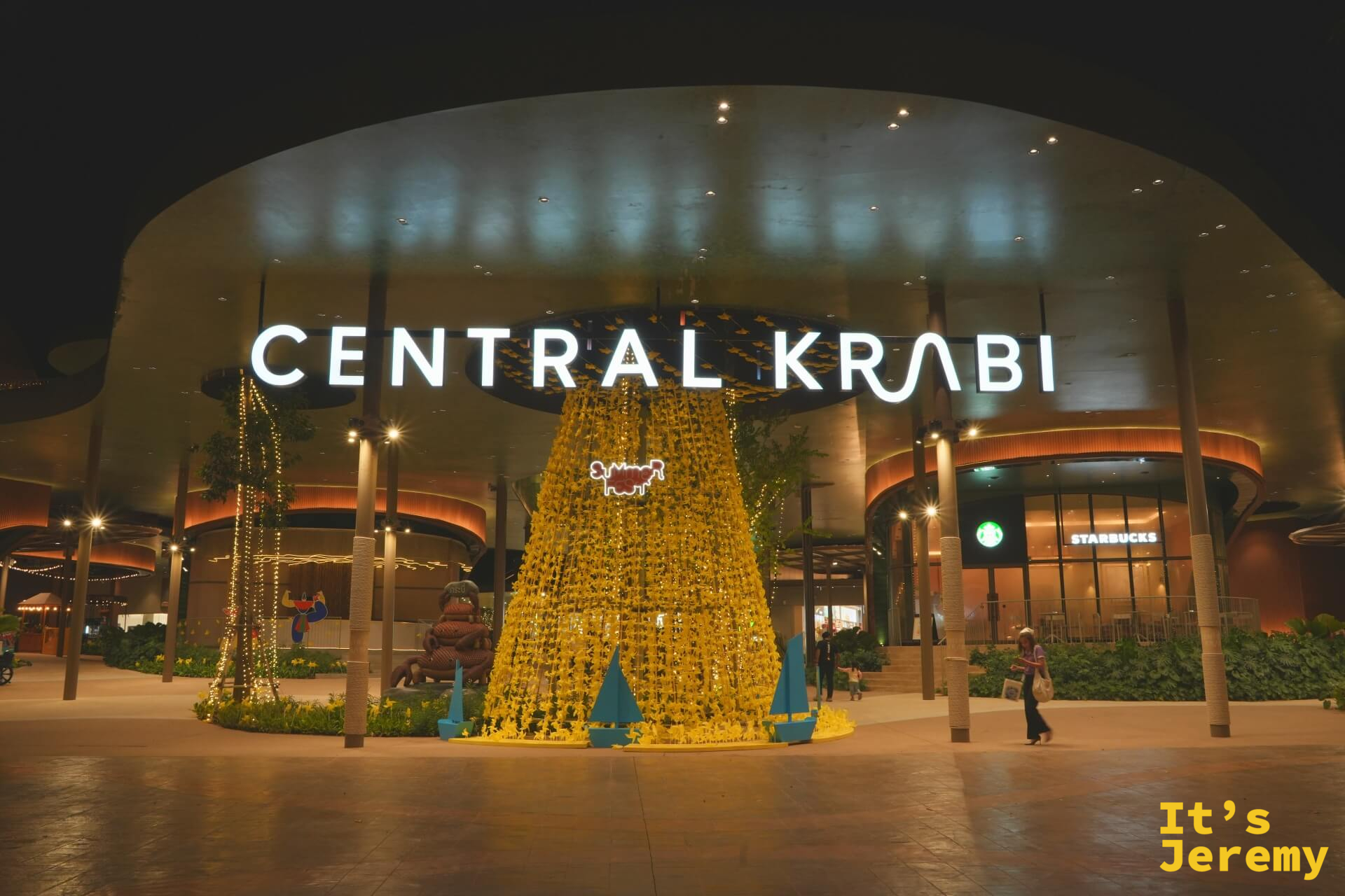 Central Krabi 夜間外觀，圓弧建築打燈，入口前有黃色花瀑裝置，右側 Starbucks 招牌