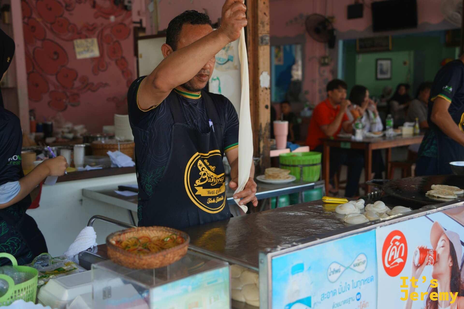 師傅將麵糰高舉拉薄，展示 Roti 的製作手法