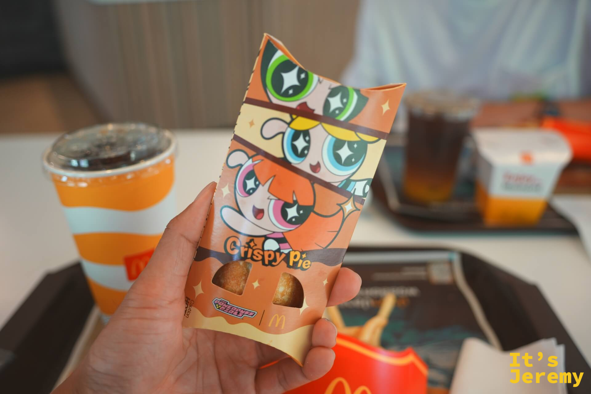 手持麥當勞 Crispy Pie 飛天小女警聯名包裝,橘色紙盒上印著飛天小女警三姐妹圖樣