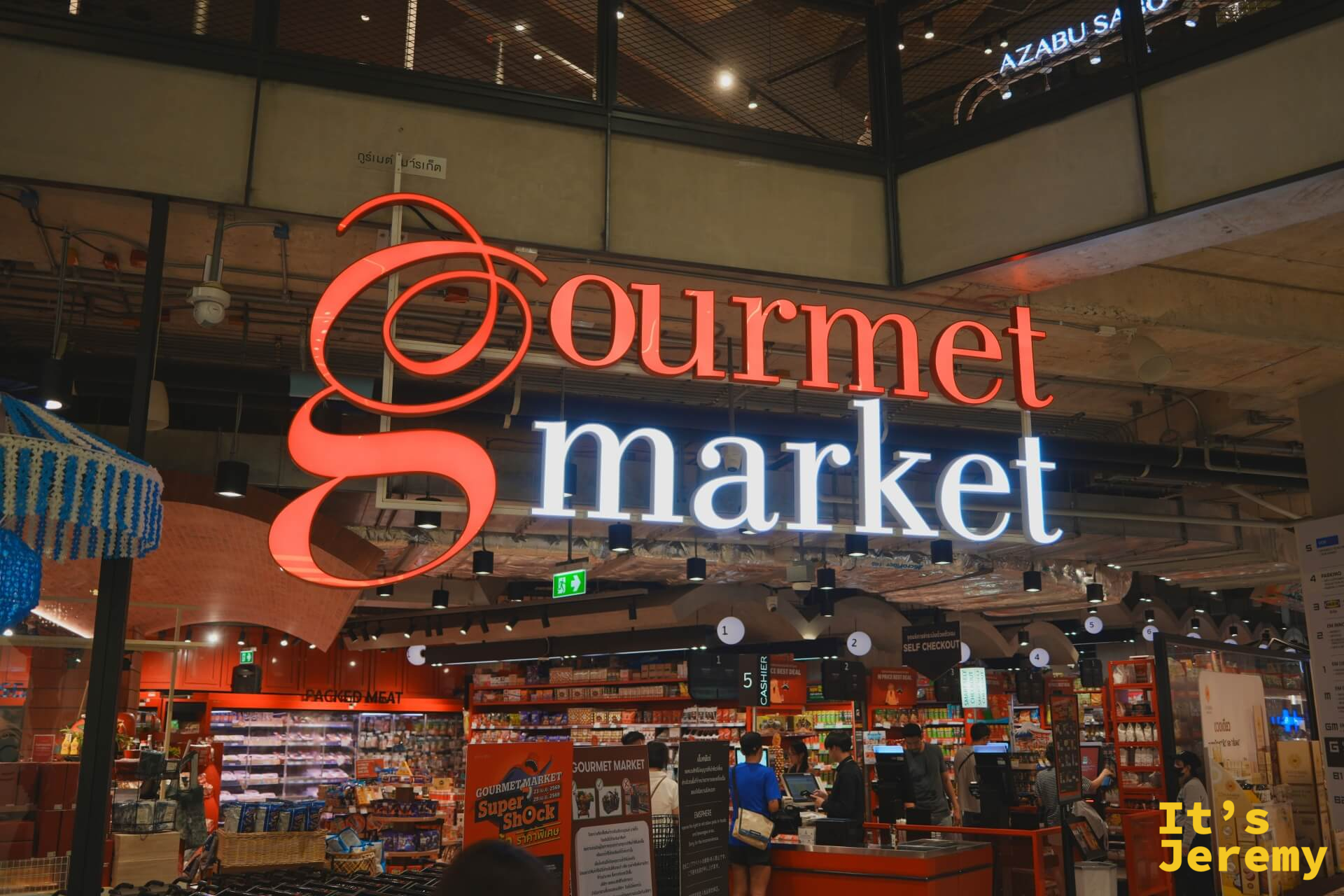 Gourmet Market 招牌特寫,紅色草書 g 字樣,藍色 market 霓虹字,櫃台忙碌中