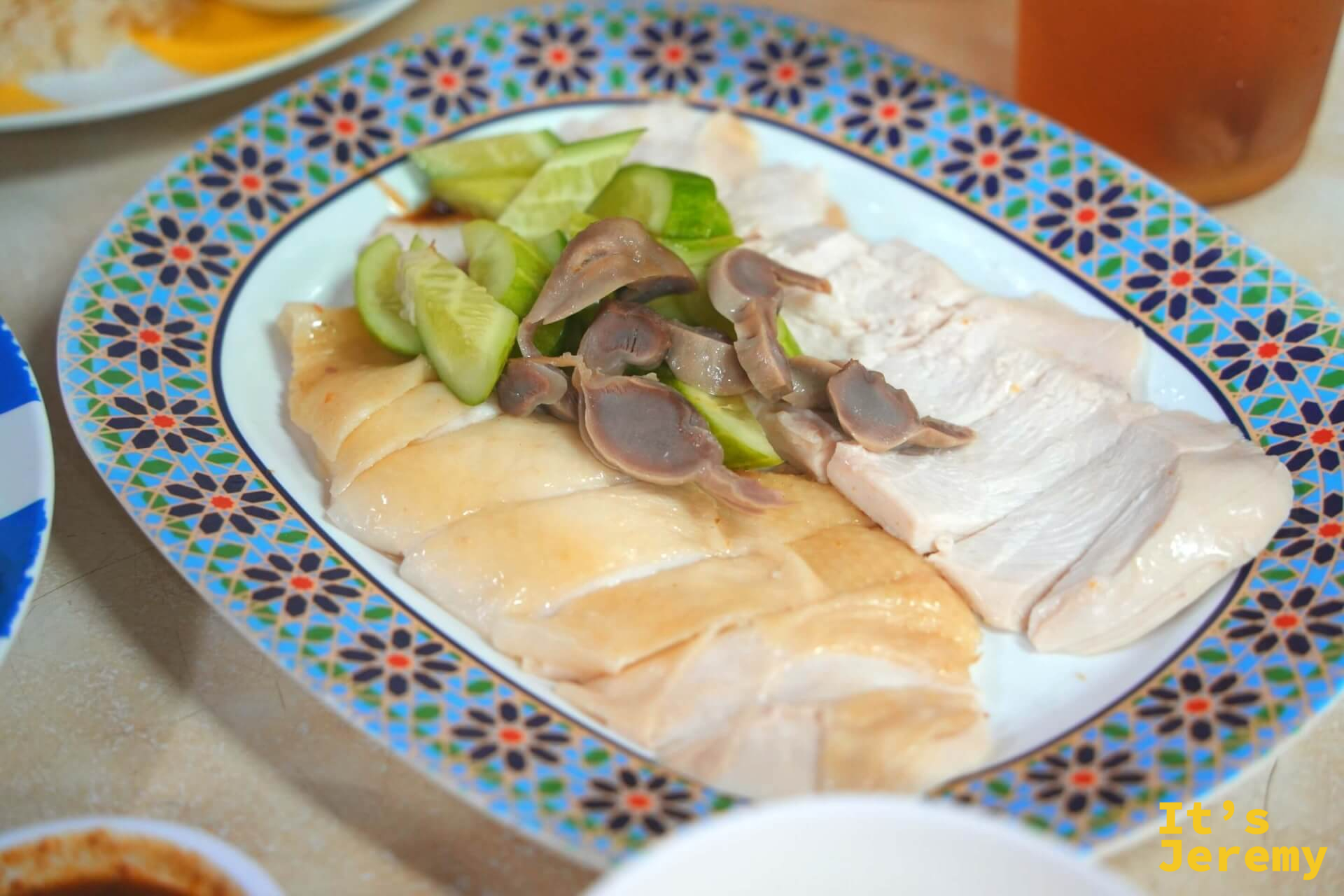 白斬雞飯整盤,嫩黃色的海南雞切片整齊排放,淋上雞油,底下鋪著雞油飯